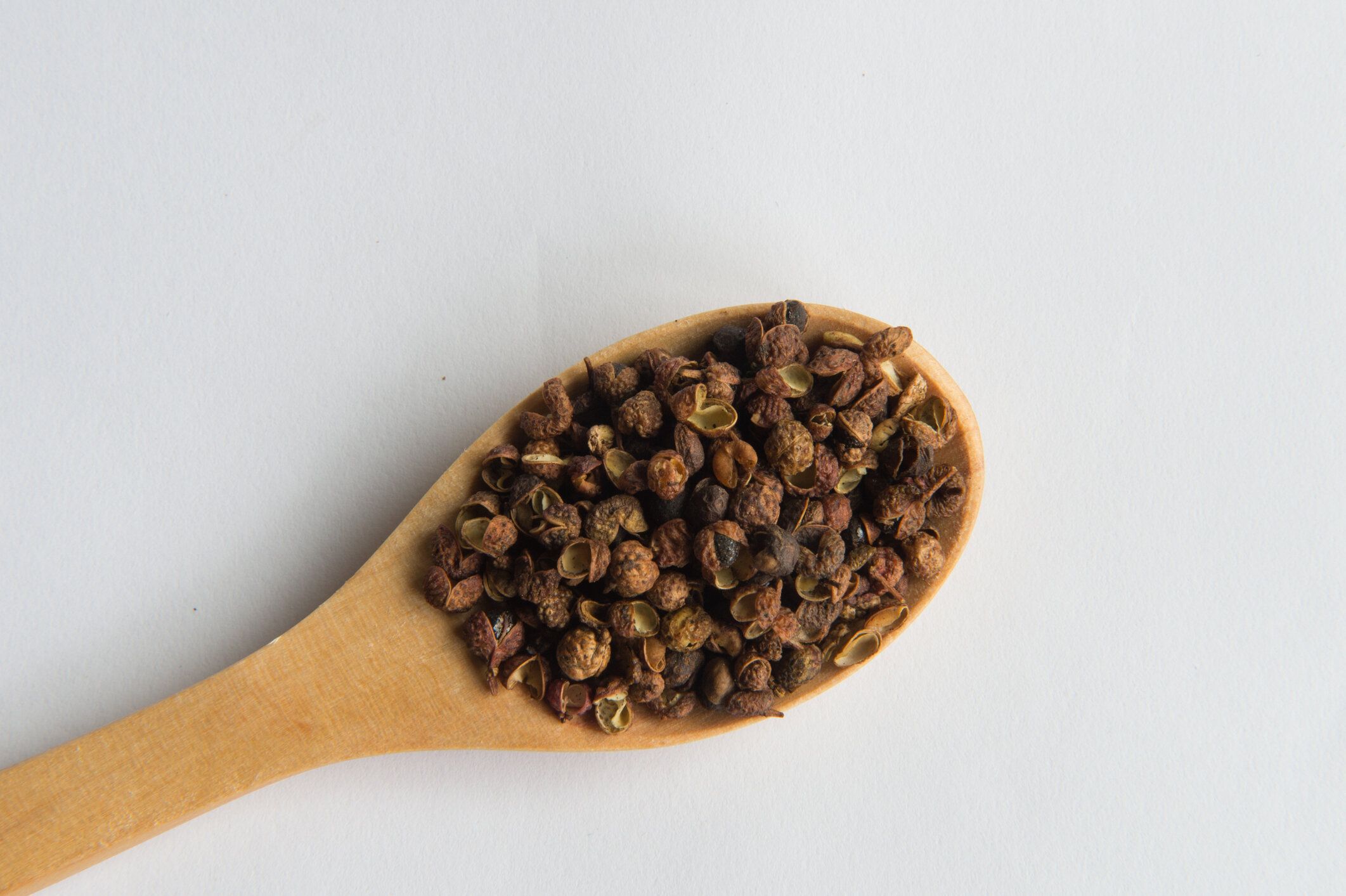 四川ペッパー ホワイト バック グラウンド (四川唐辛子) に分離された木製のスプーンで