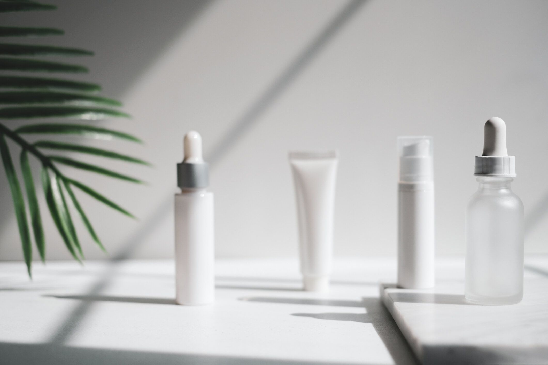 化粧品スキンケア包装.自然光と影を持つ豪華な白い大理石に美容製品モックアップ。