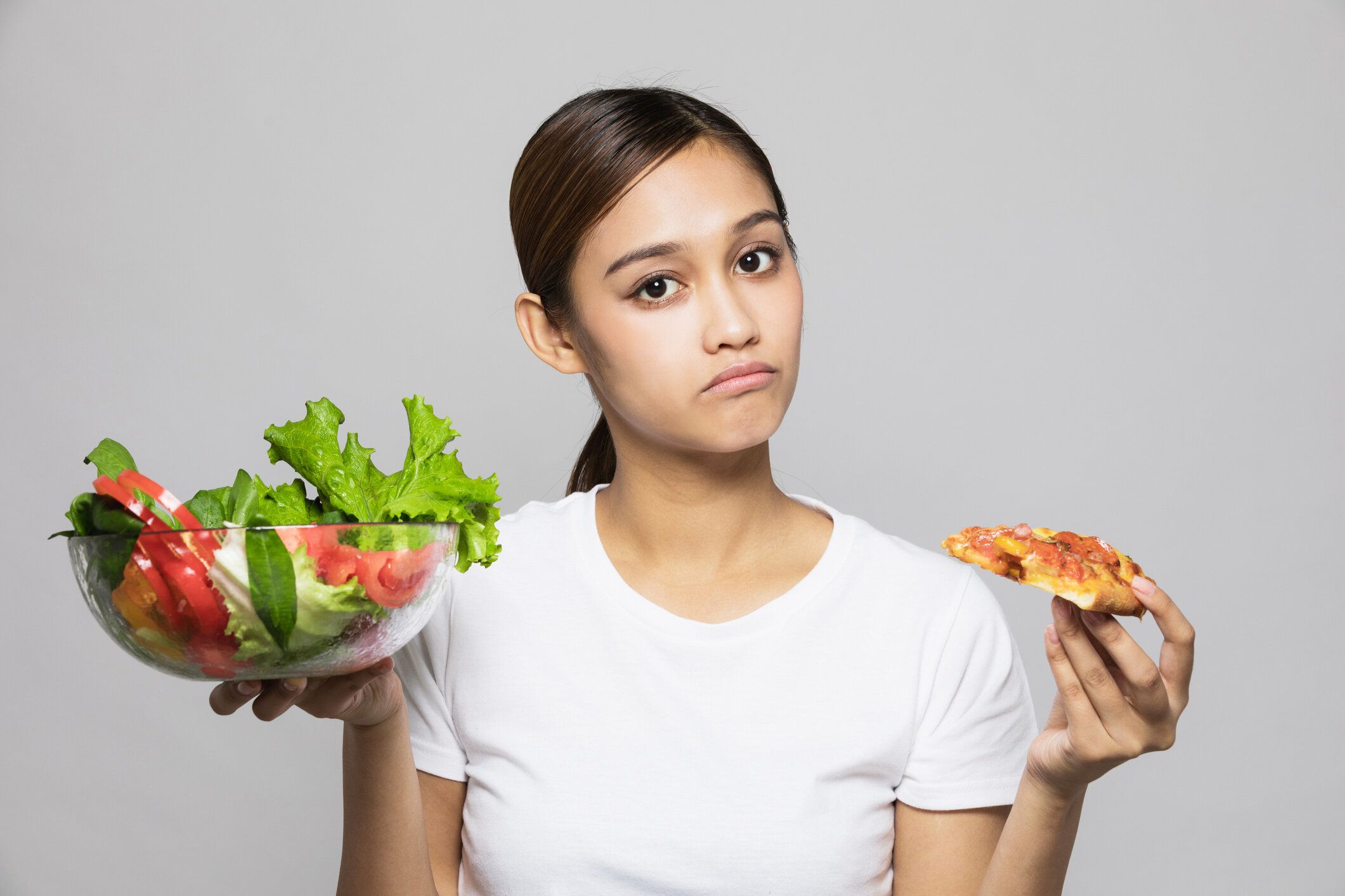 サラダボウルとピザを保持している若い女性。