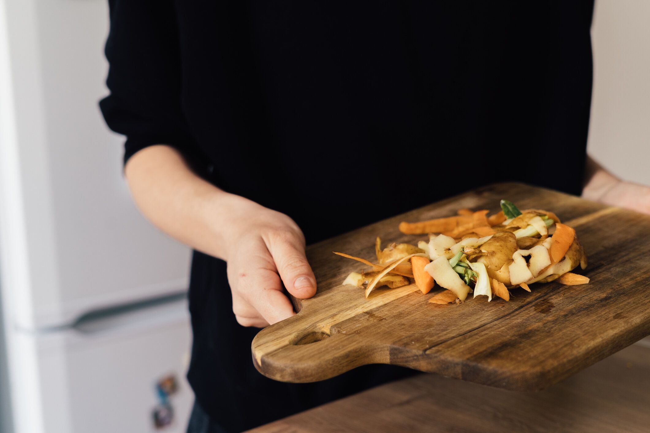 キッチン廃棄物から堆肥をリサイクルするミレニアル世代の若い女性。循環経済、実物、有機廃棄物