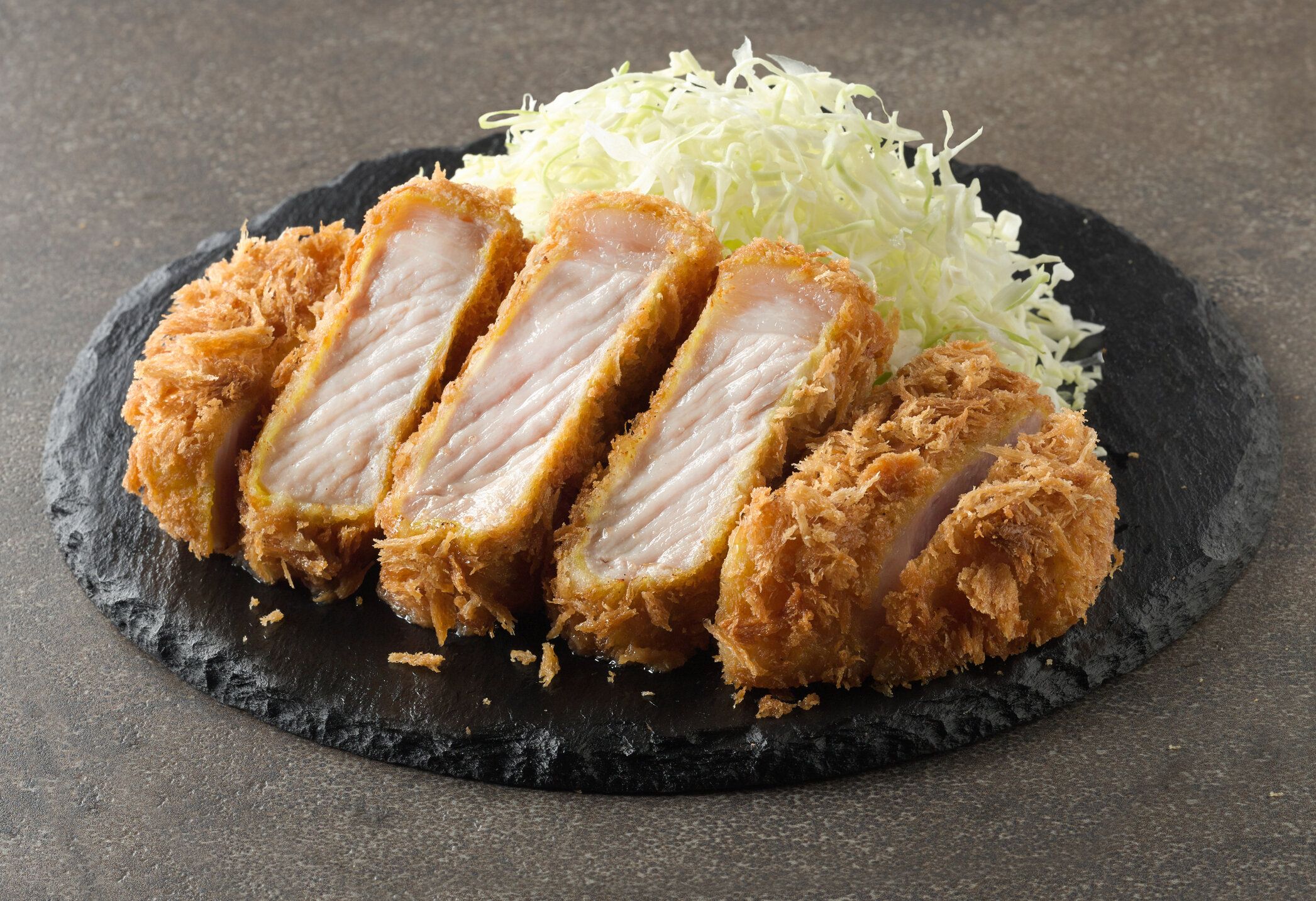 ブラックプレートにキャベツを入れた揚げ豚カツ。家庭料理のコンセプト