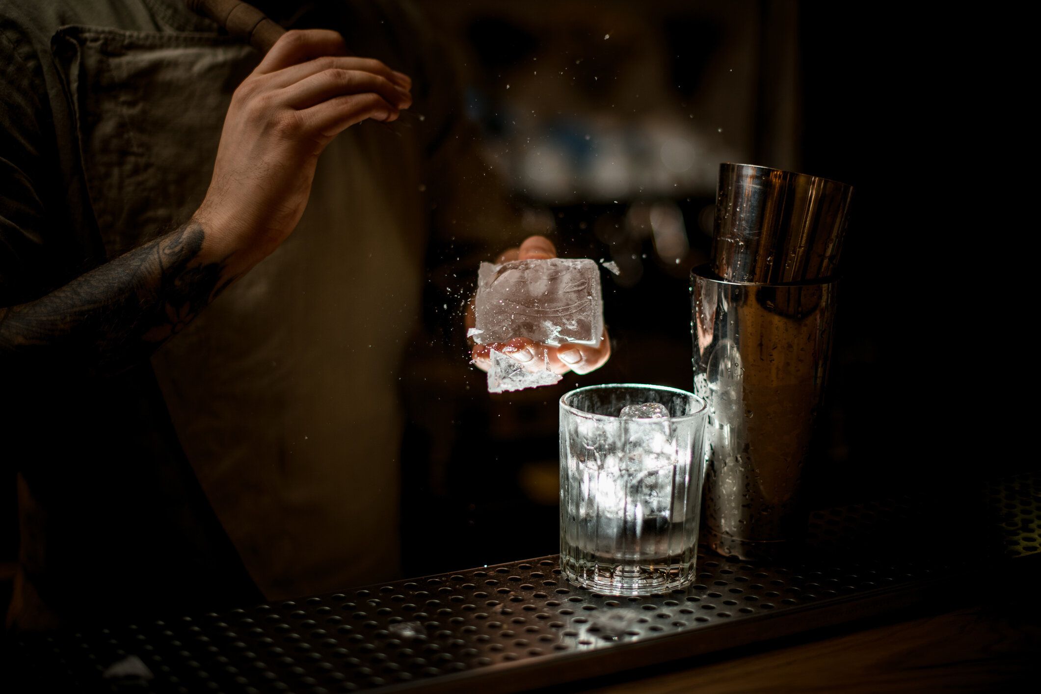 男は氷を保持し、そこから正確な破片を壊し、眼鏡が近くに立っています