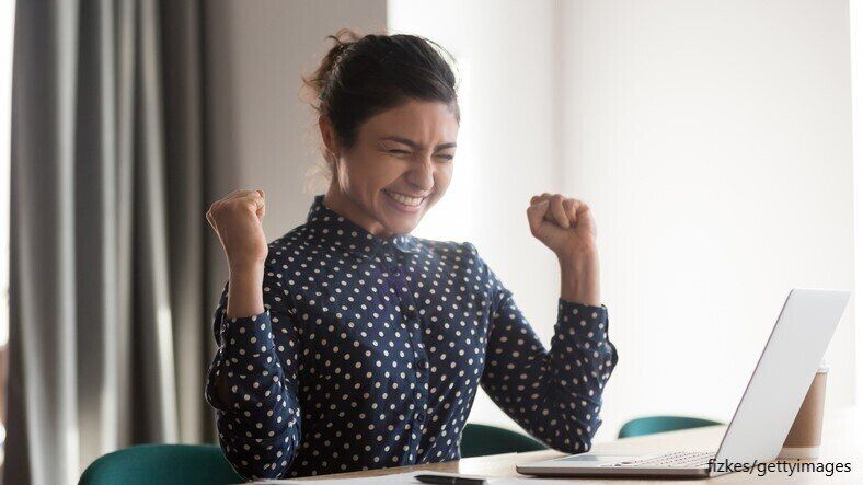パソコンの前に喜ぶ女性