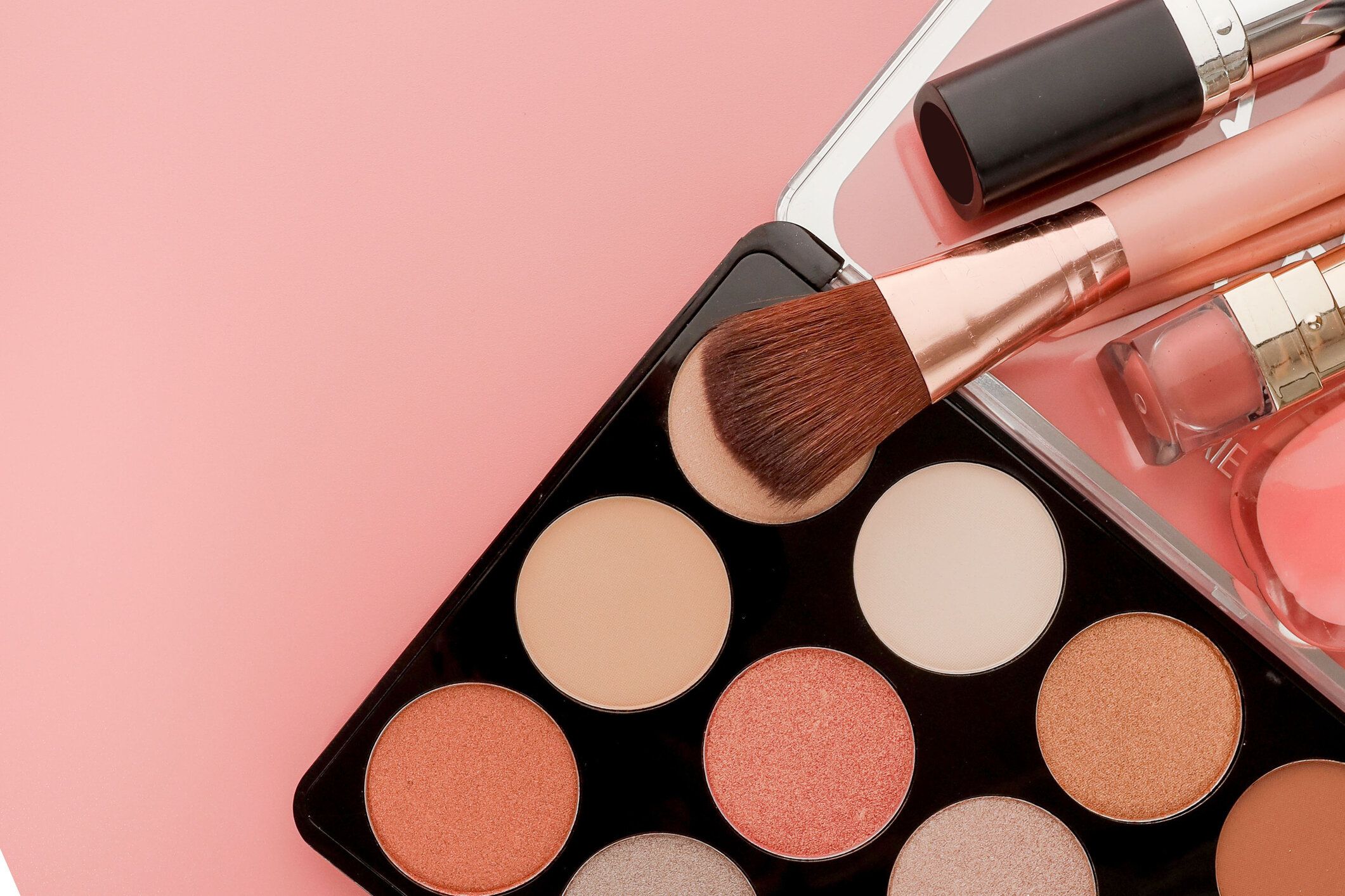 コピースペース付きピンクの背景に様々なメイクアップ製品