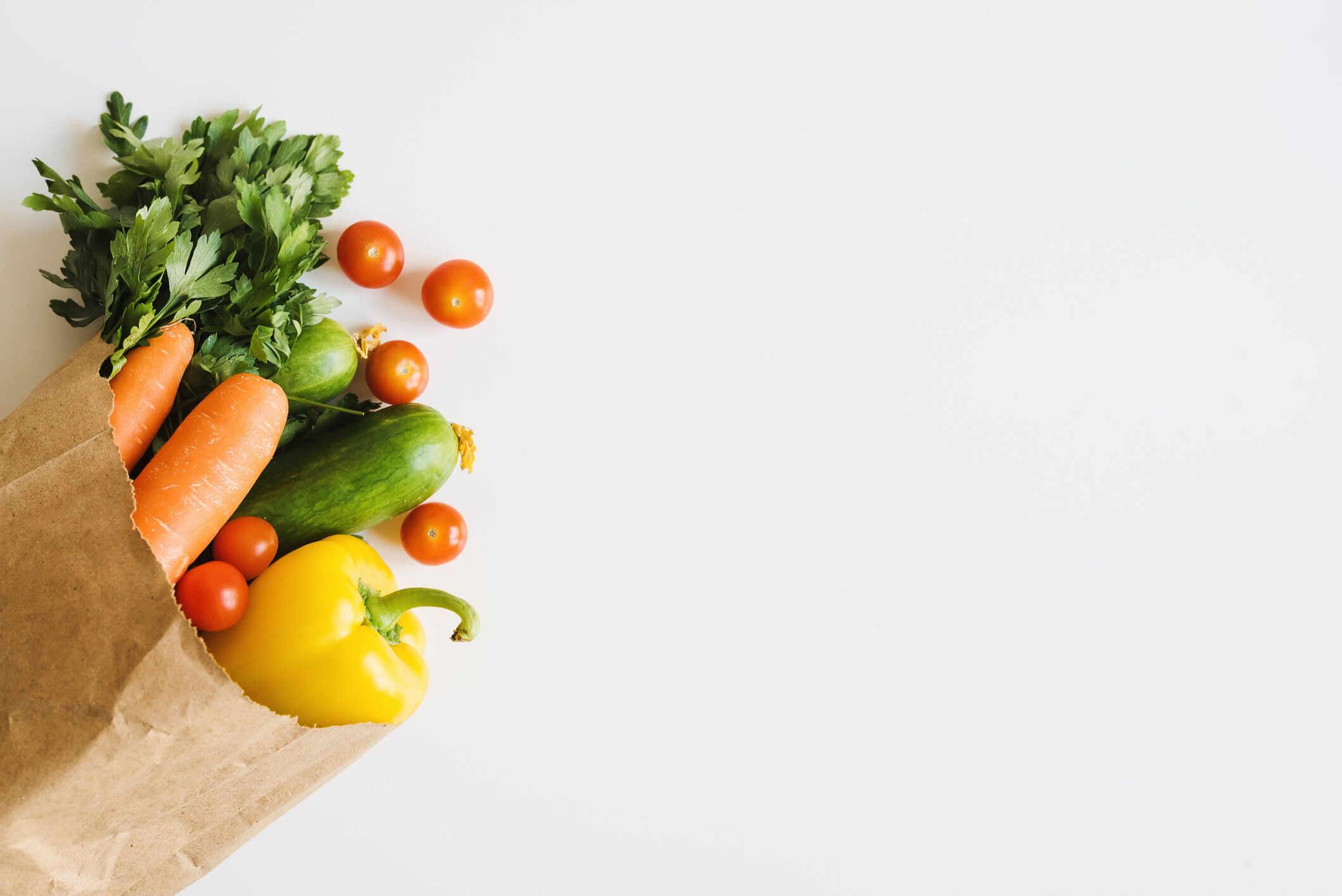 白い背景、トップビューにエコフレンドリーな紙袋に新鮮な野菜やハーブ。食品の配達。食料品の買い物