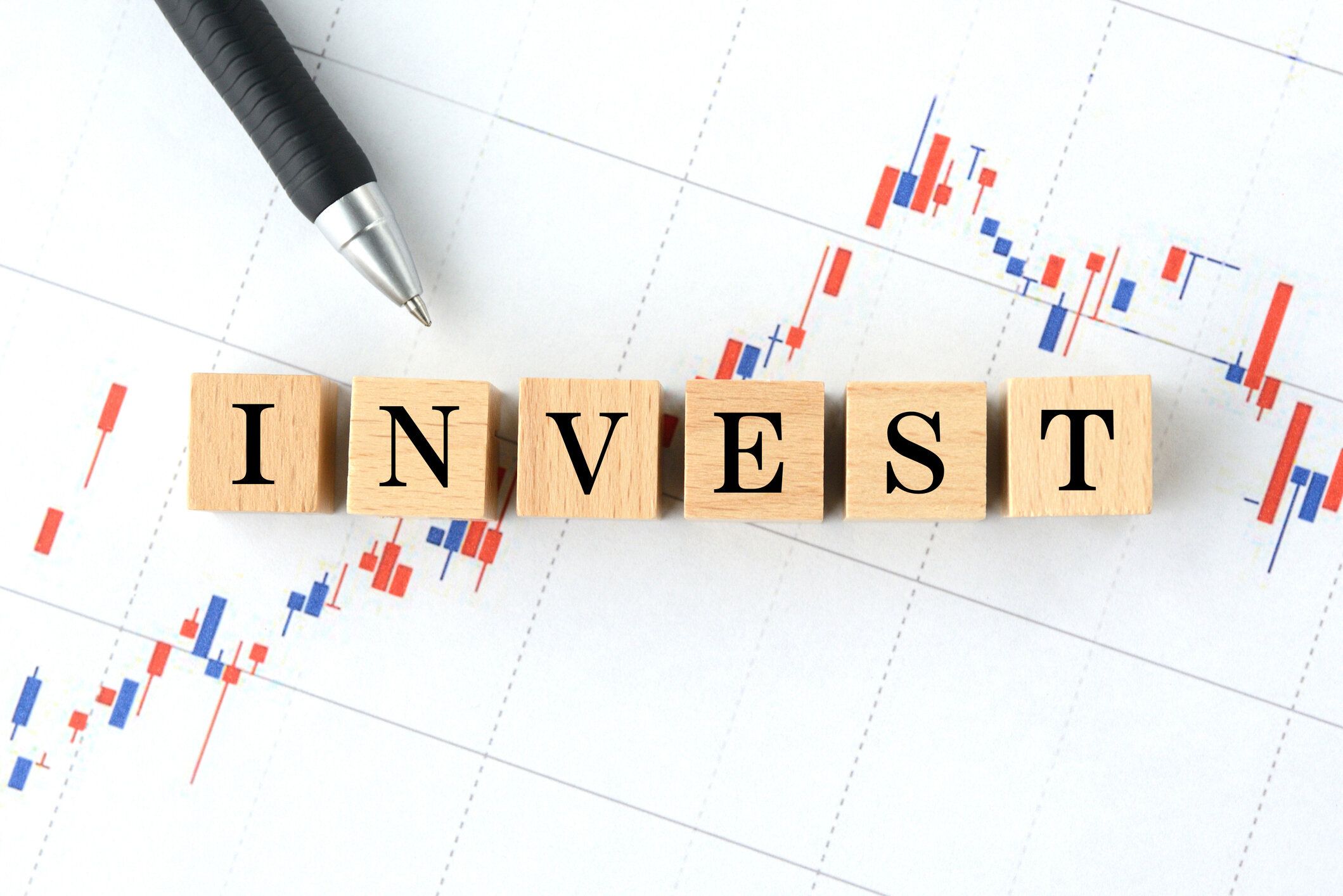 ストックチャートグラフ上の投資語付き木製ブロック