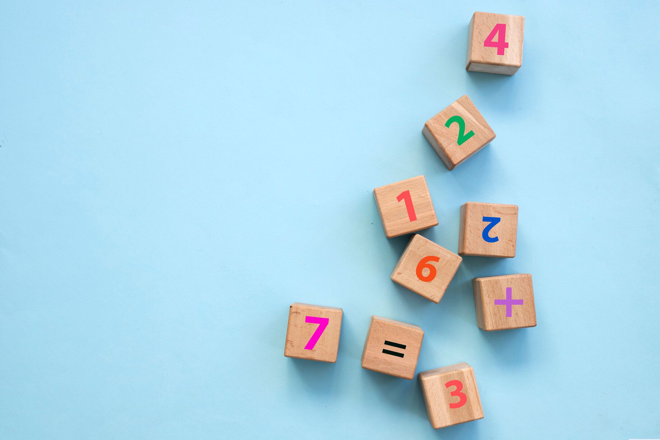 ターコイズの木製のテーブルの背景にカラフルなレンガのトップビュー。数字と算術記号。教育コンセプト