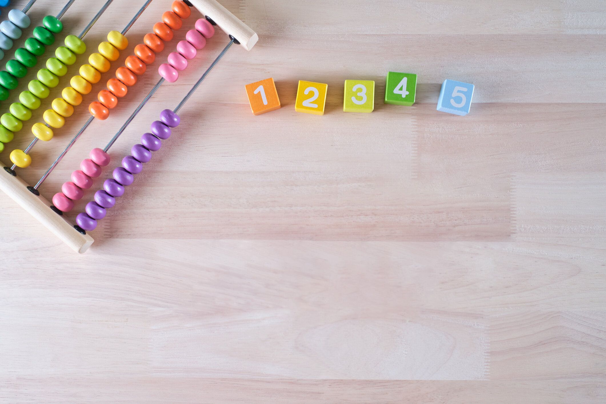 フラットレイ、明るい色の木製レンガとそろばんのおもちゃの背景のトップビューは、テキスト、子供の開発、初期の数学のスキルの概念のためのコピースペースを持っています