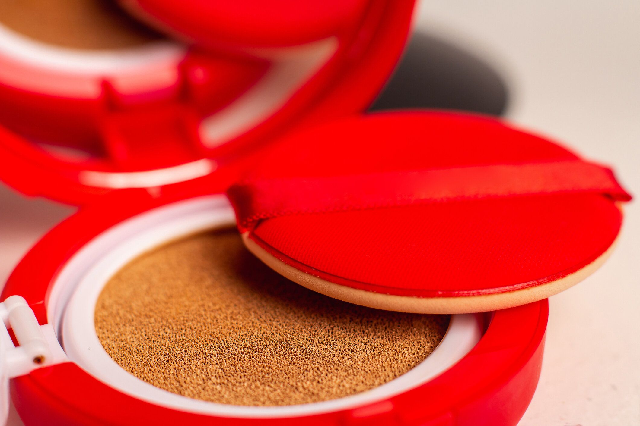 白い背景にスポンジとパフとファンデーションクッション。