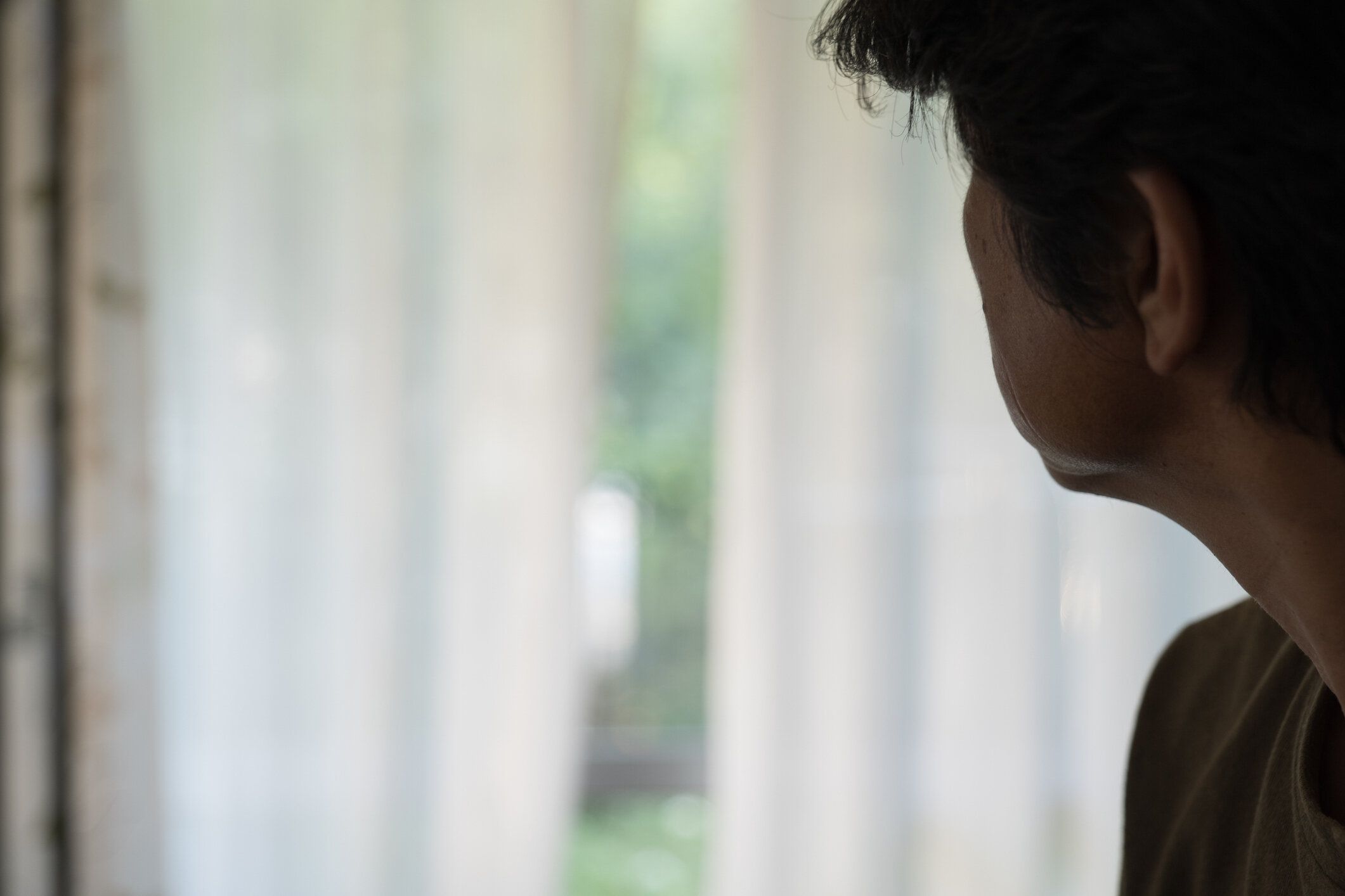 庭を見つめて考える中年男性