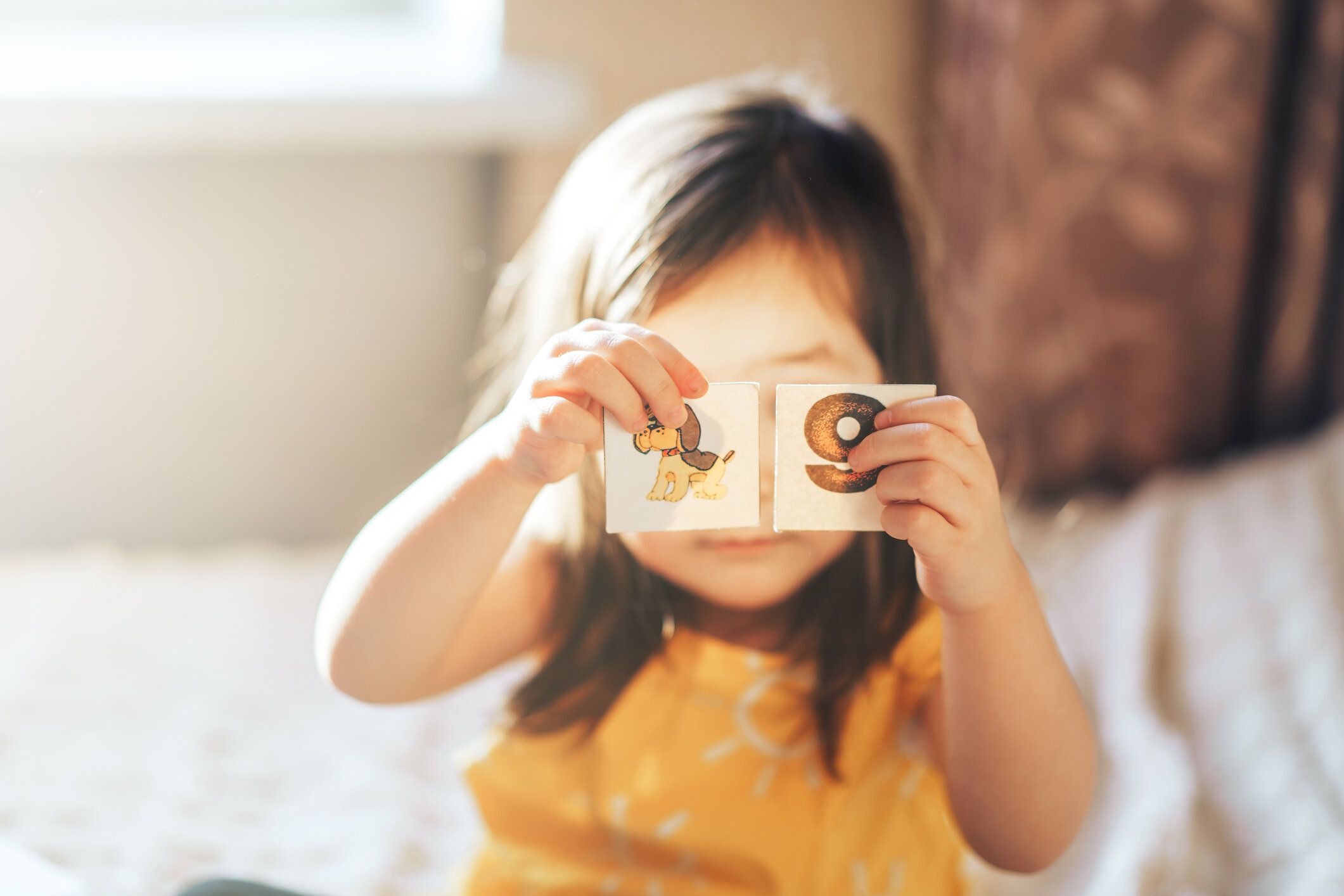 子供はベッドの上の部屋で教育ゲームをします。子供はカードで数字と文字を学びます。子育てと子育て