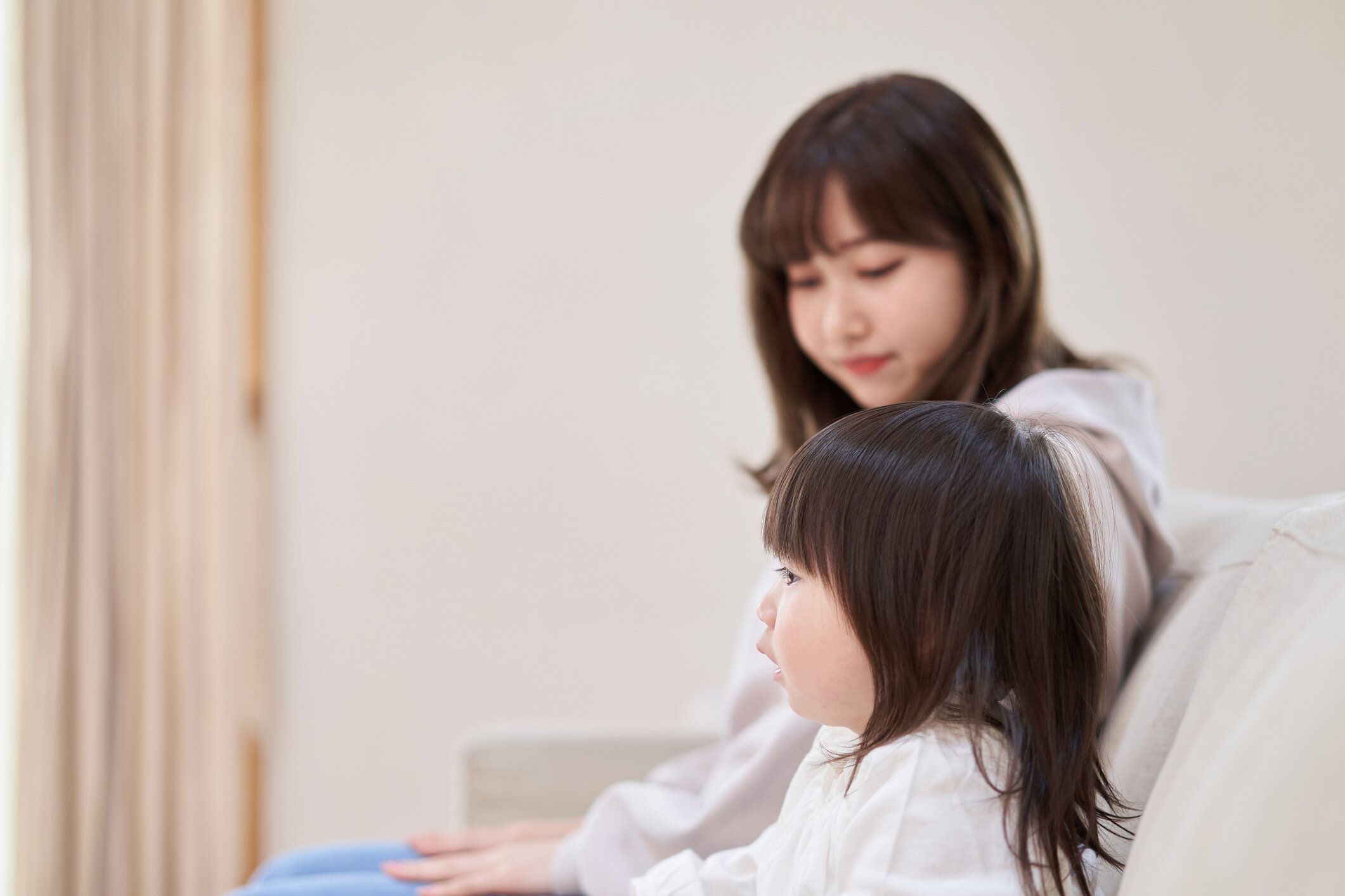 アジアの女の子とお母さんはテレビを見て