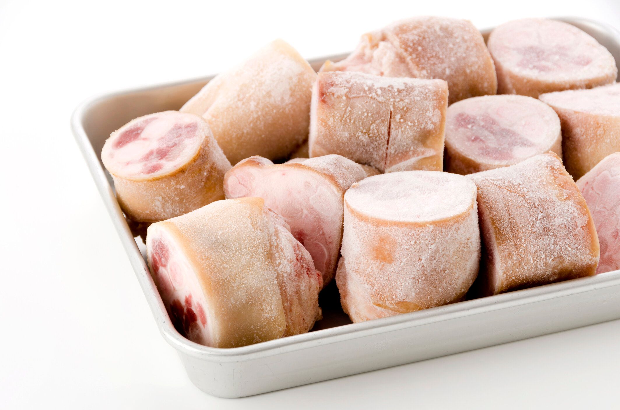 白い背景のアルミニウム皿の新鮮な未加工ブタのフィート