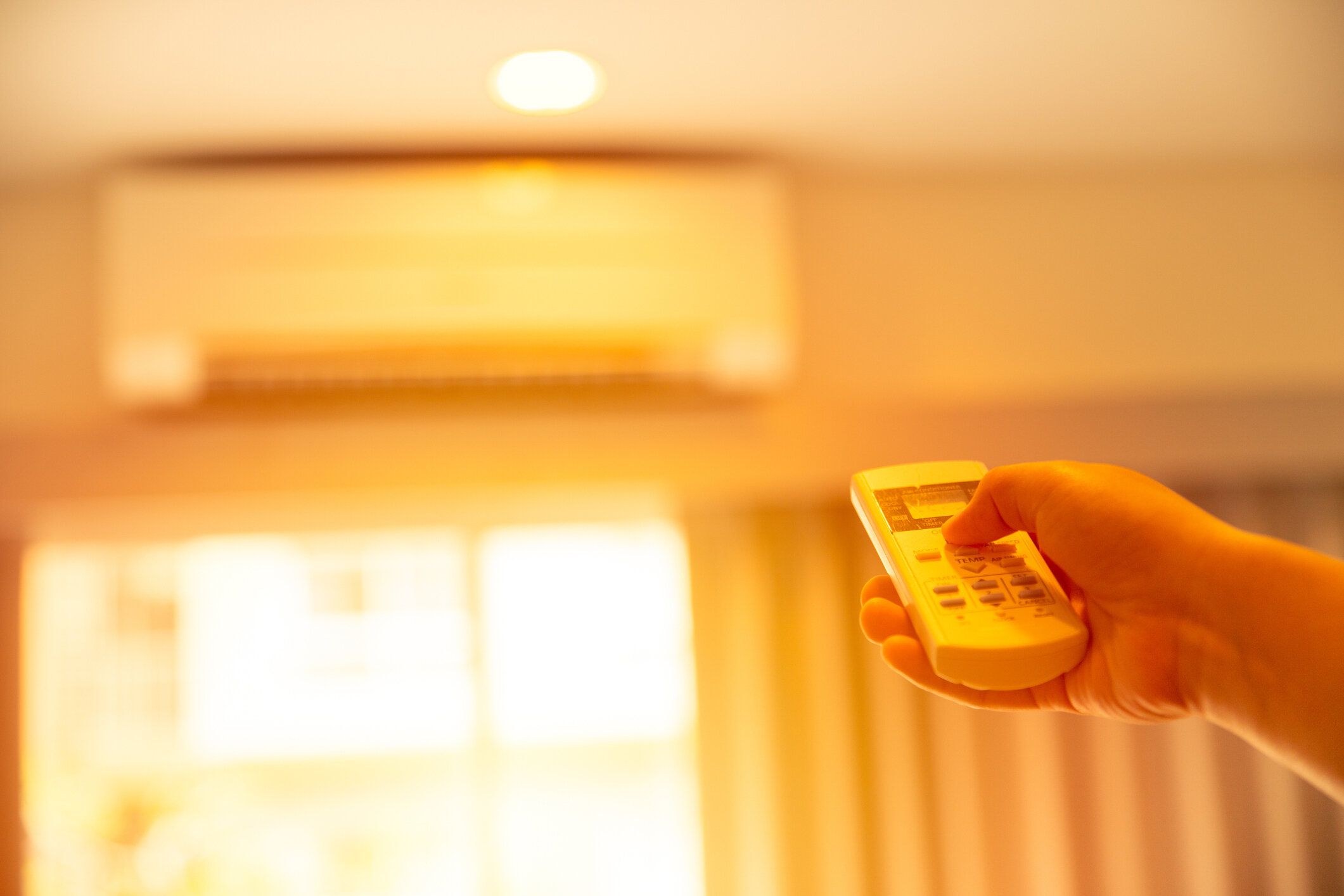 手型エアコン ホーム夏の非常に暑い日に冷房を壁にリモコン付きエアコンの温度を調整します。