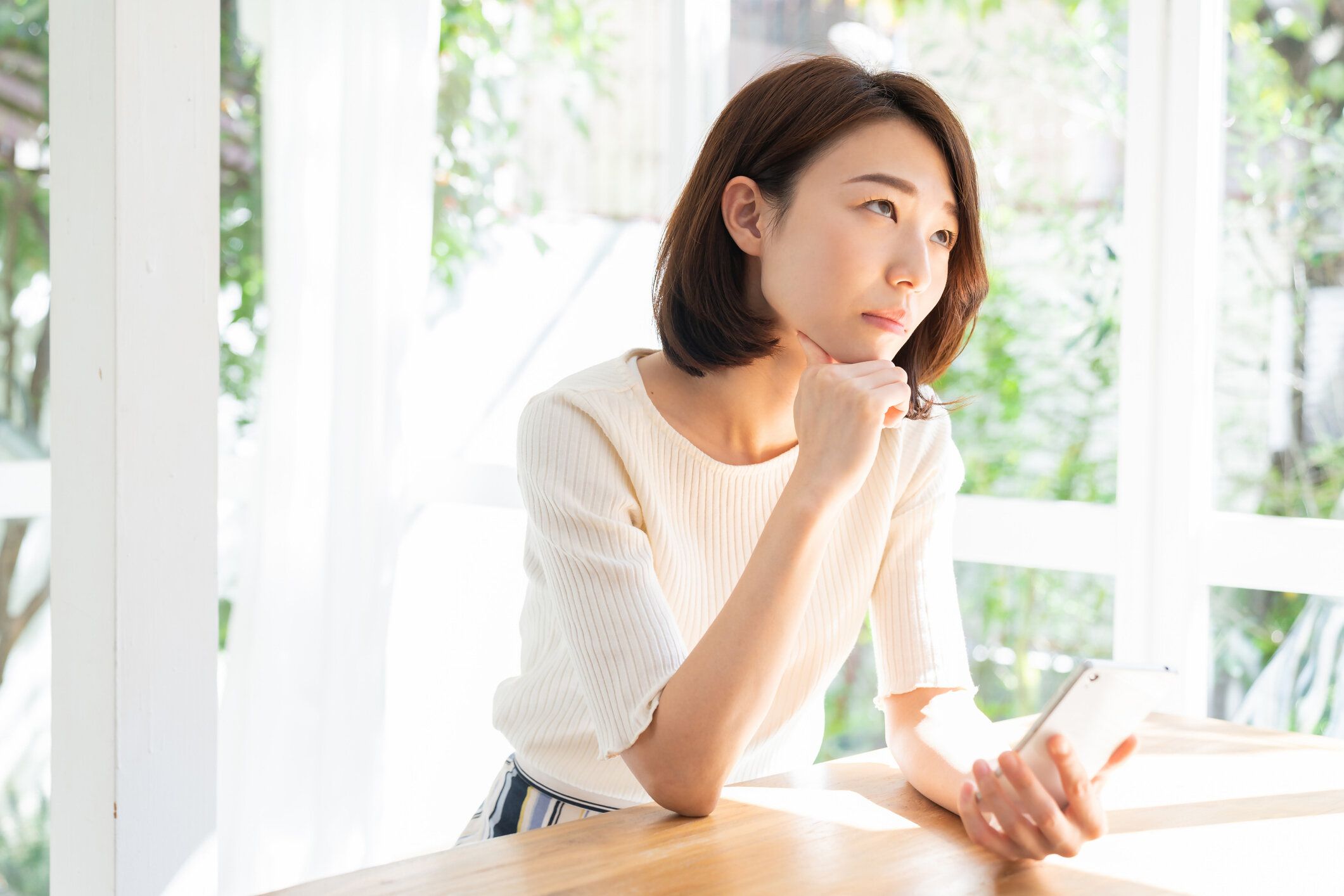 スマート フォンを見て魅力的なアジアの女性、考える、