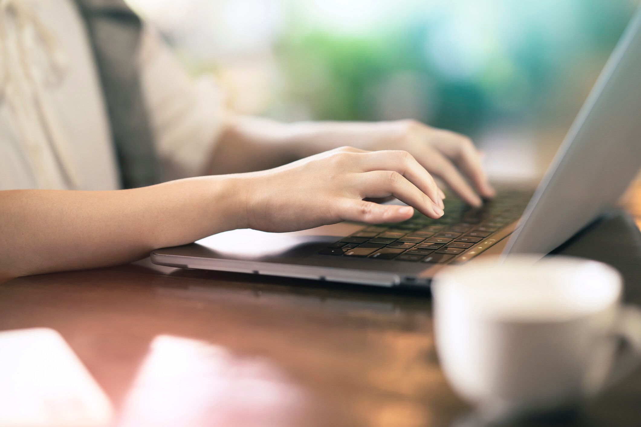 ラップトップを操作する若い女性の手