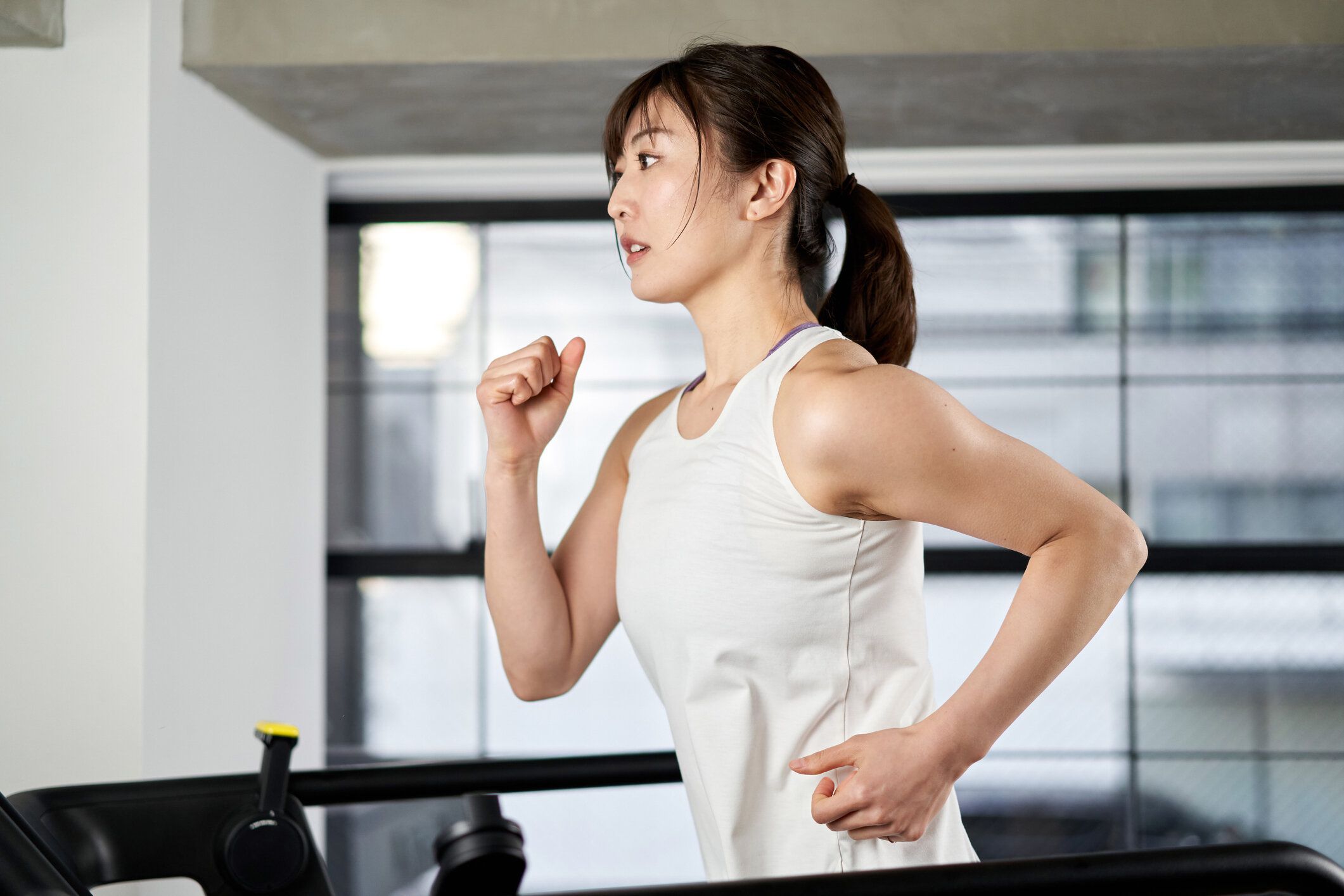 トレーニングジムでトレッドミルで走るアジアの女性