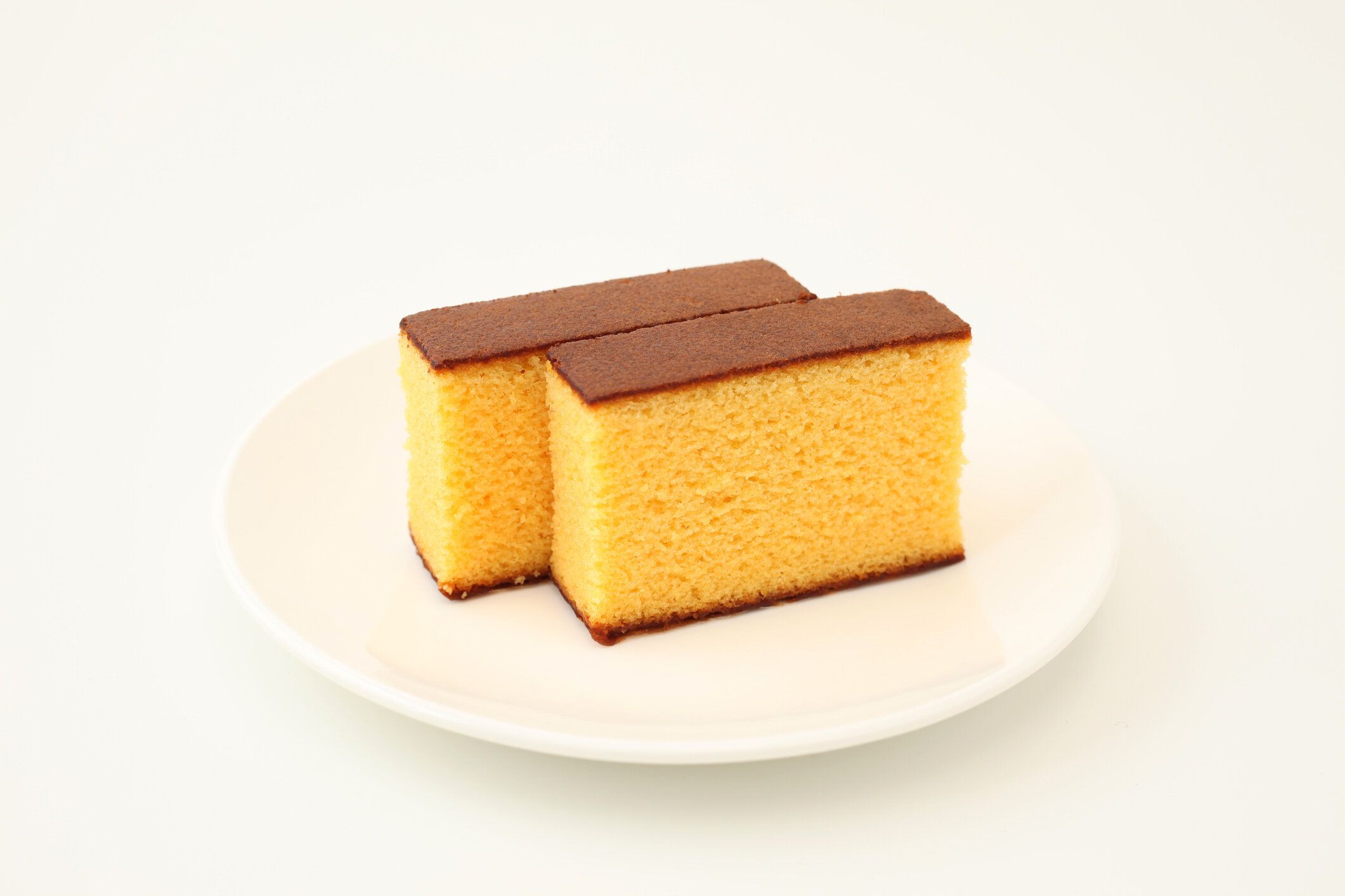 白い背景の上のプレートに日本スポンジ カステラ