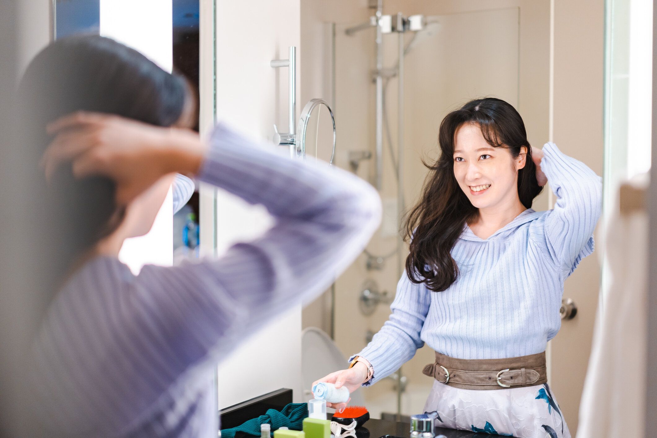 鏡の前で髪をしている若い女性