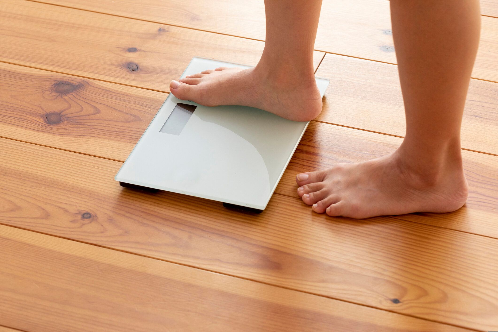 木製の床と体重計に若い女性の足
