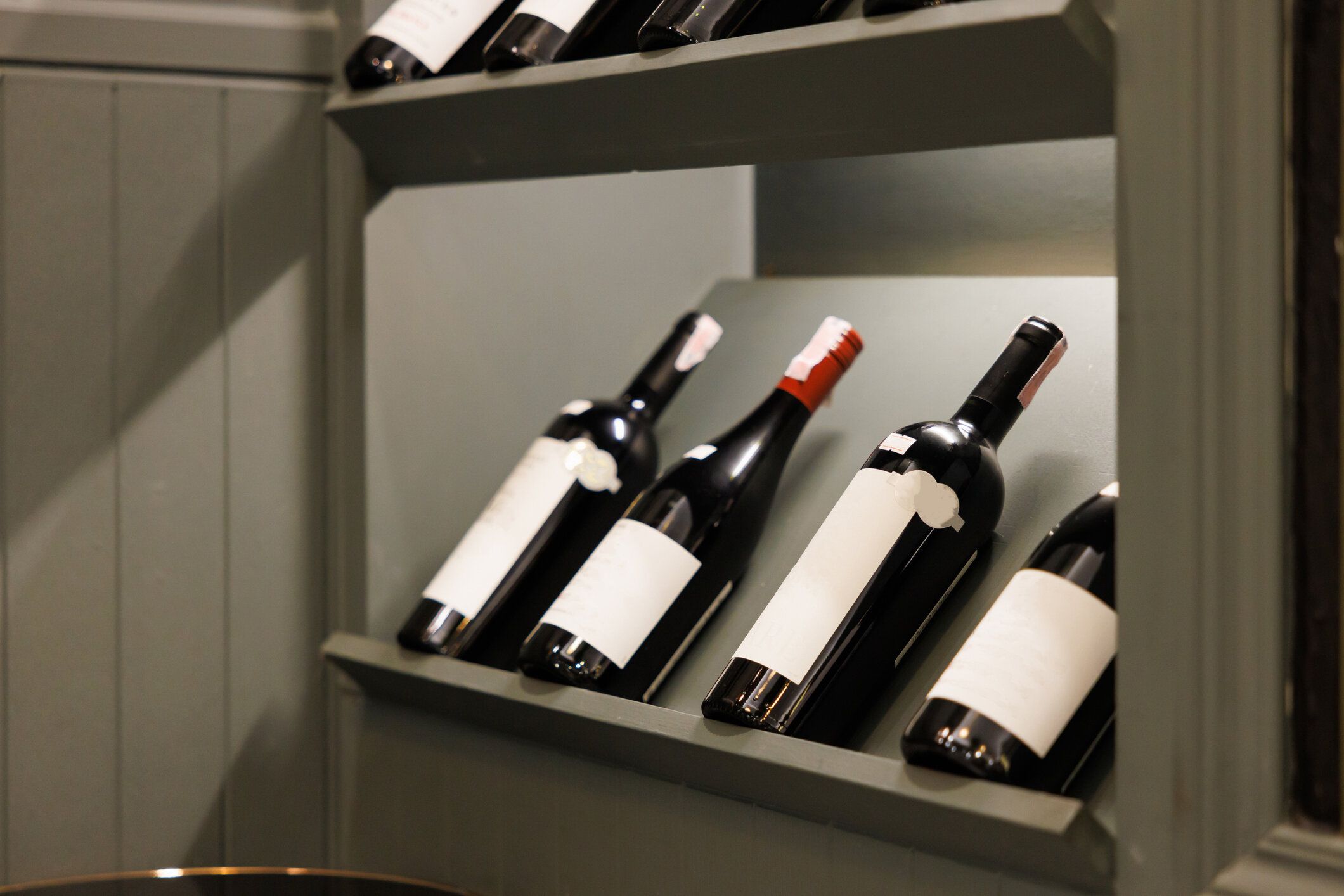 ワインボトルは木製のワイン棚に寄りかかっています。家の室内装飾のコンセプト用のワイン棚。