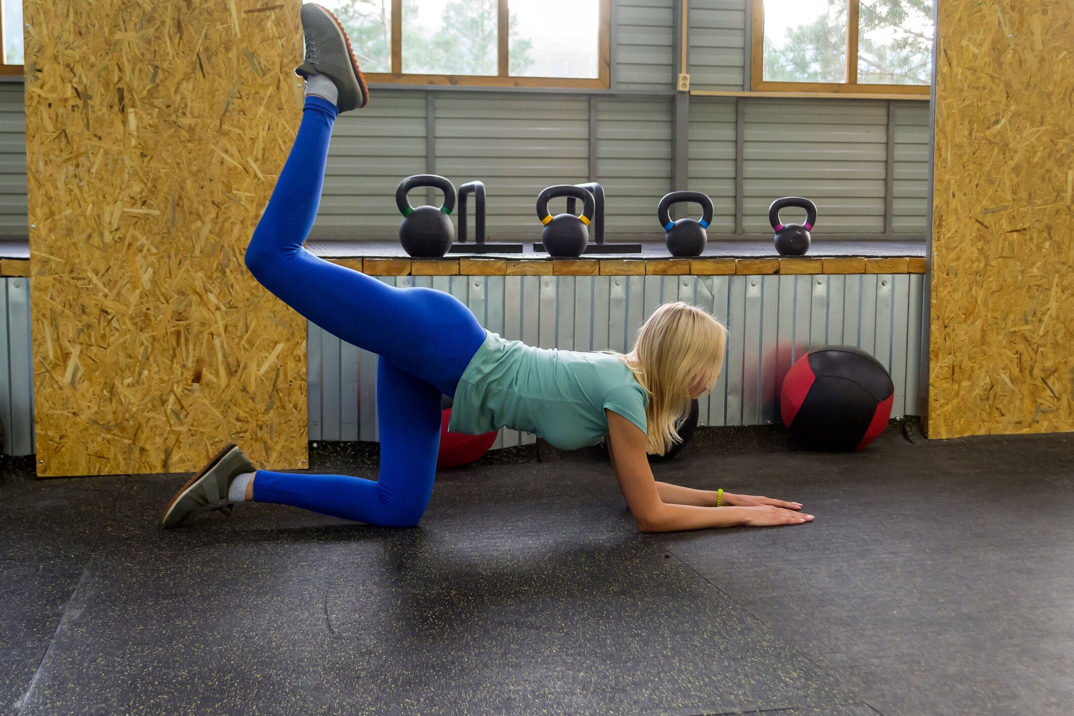 スリムな若いロバを蹴り女の子が四つんばいアーチ運動健康のスポーツ バック コンセプトを脚を矯正、スポーツ、フィットネス、ライフ スタイル。床にひざまずいて、屋外を片足を上げま�