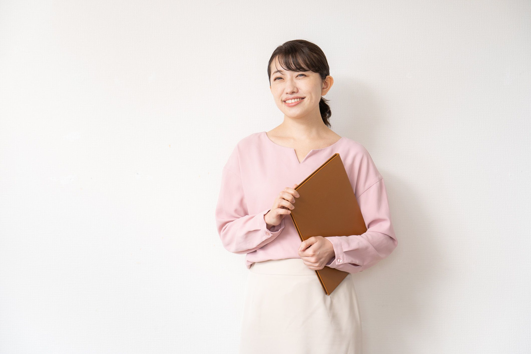 白い壁の前に立つビジネスウーマン