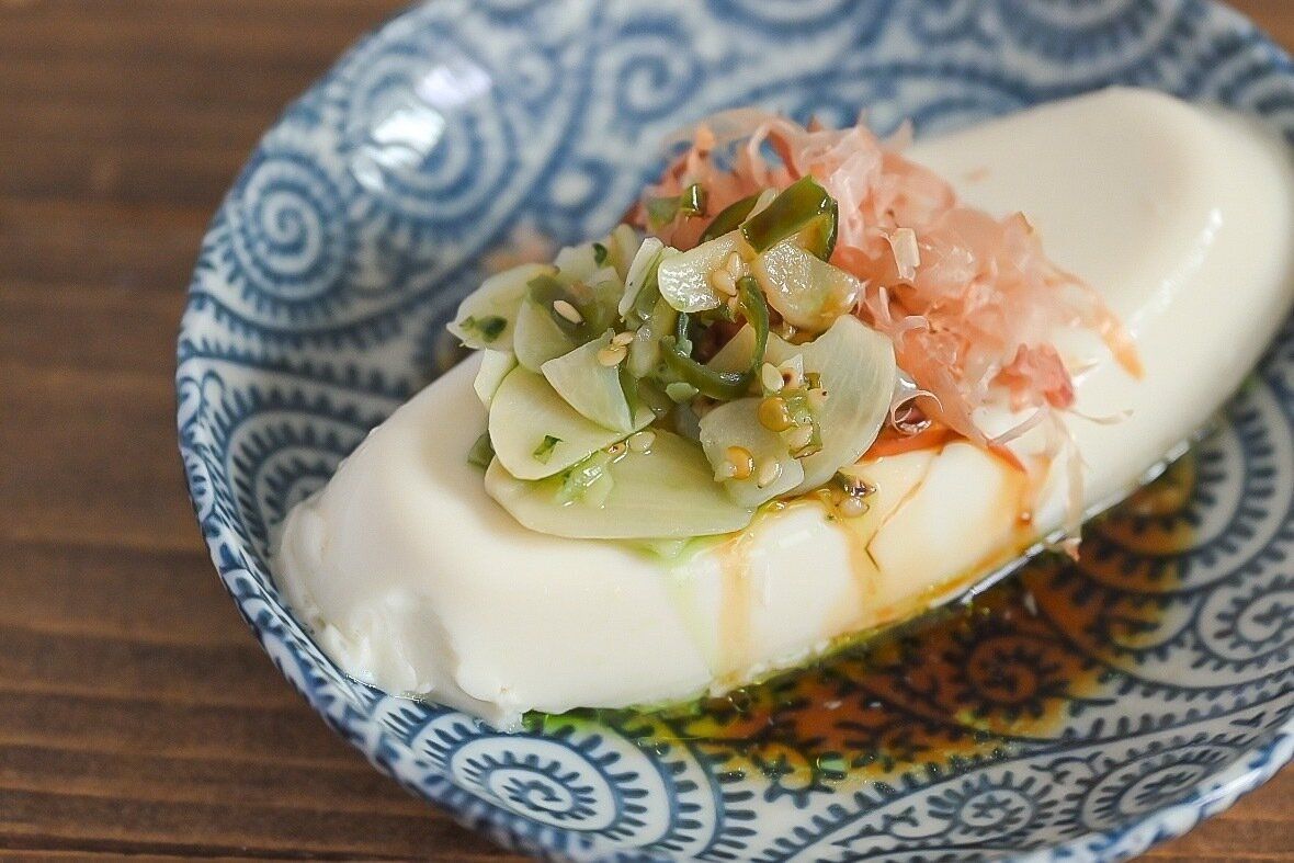 皿に盛られた青いにんにくをのせた豆腐