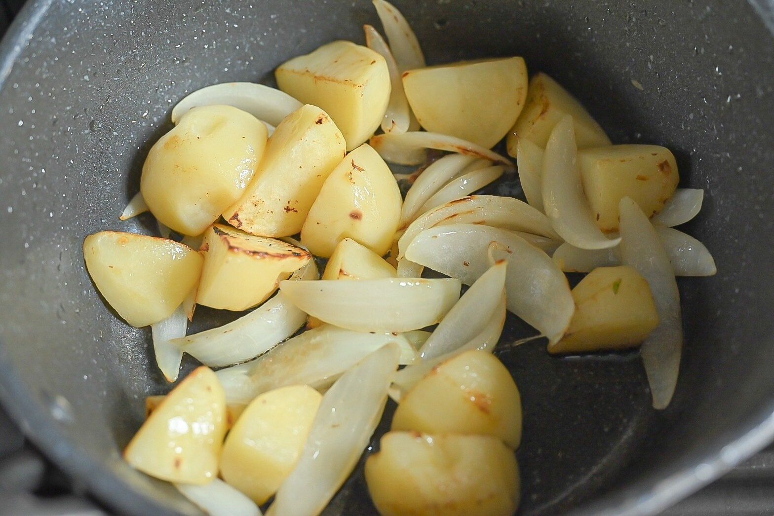 鍋に入った炒められた玉ねぎとじゃがいも