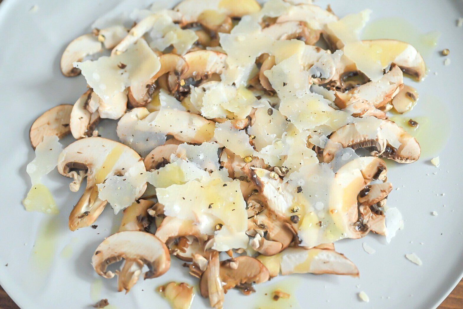 白い皿に盛られたマッシュルームのカルパッチョ