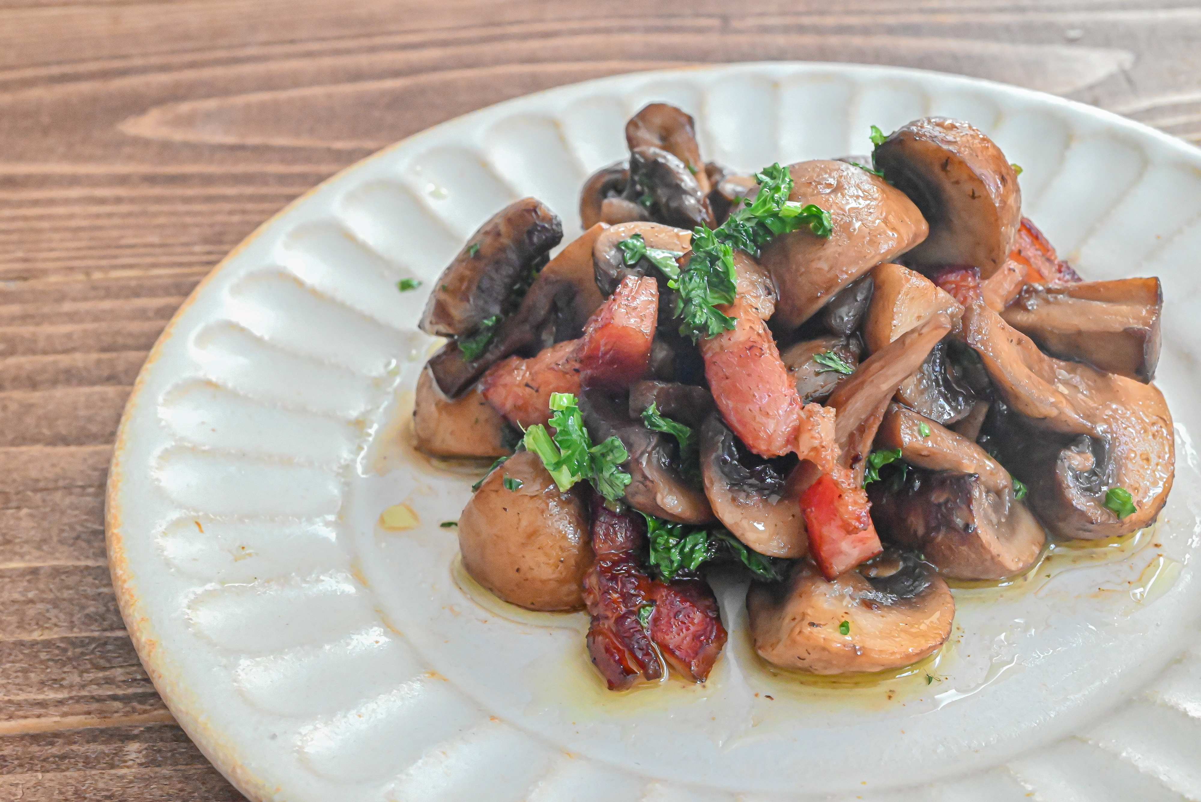 白い皿に盛られたマッシュルームとベーコン炒め