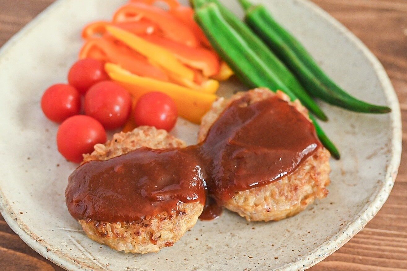 陶器の皿に盛られたオートミールハンバーグと添えられたハンバーグ