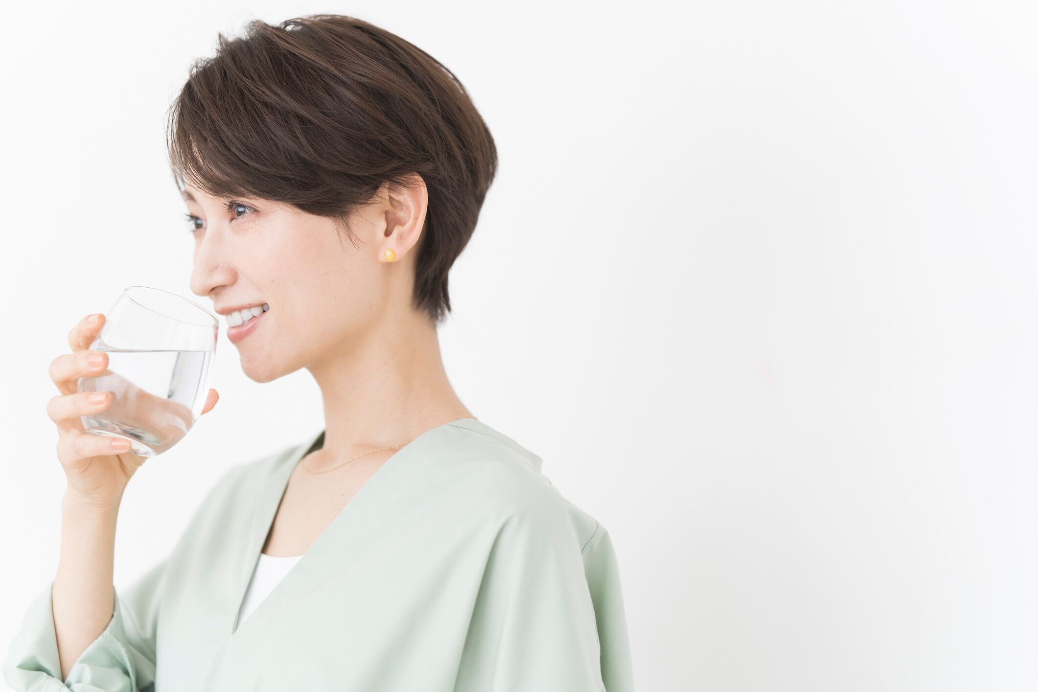 アジア人女性がコップ一杯の水を飲んでいる。