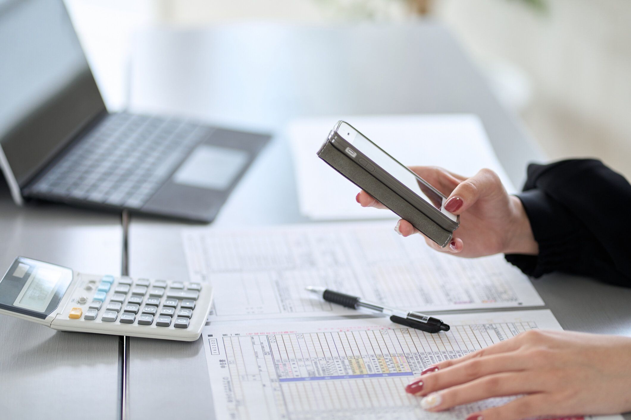 スマートフォンで納税申告書を提出するアジア人女性