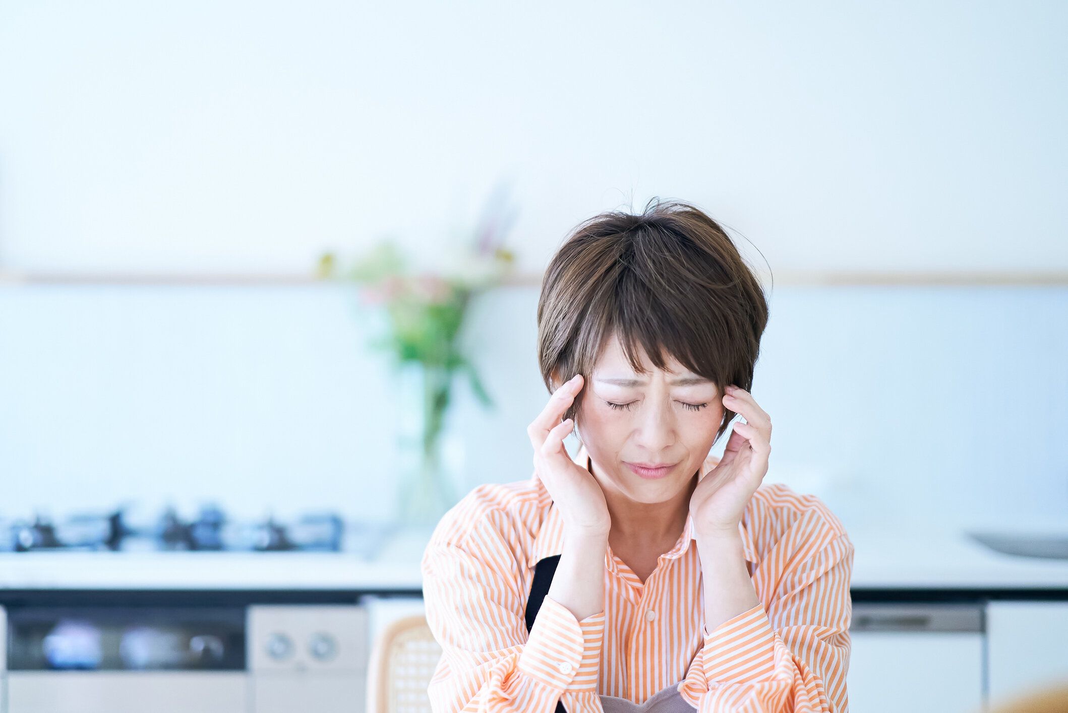 頭痛に苦しむエプロンの女性
