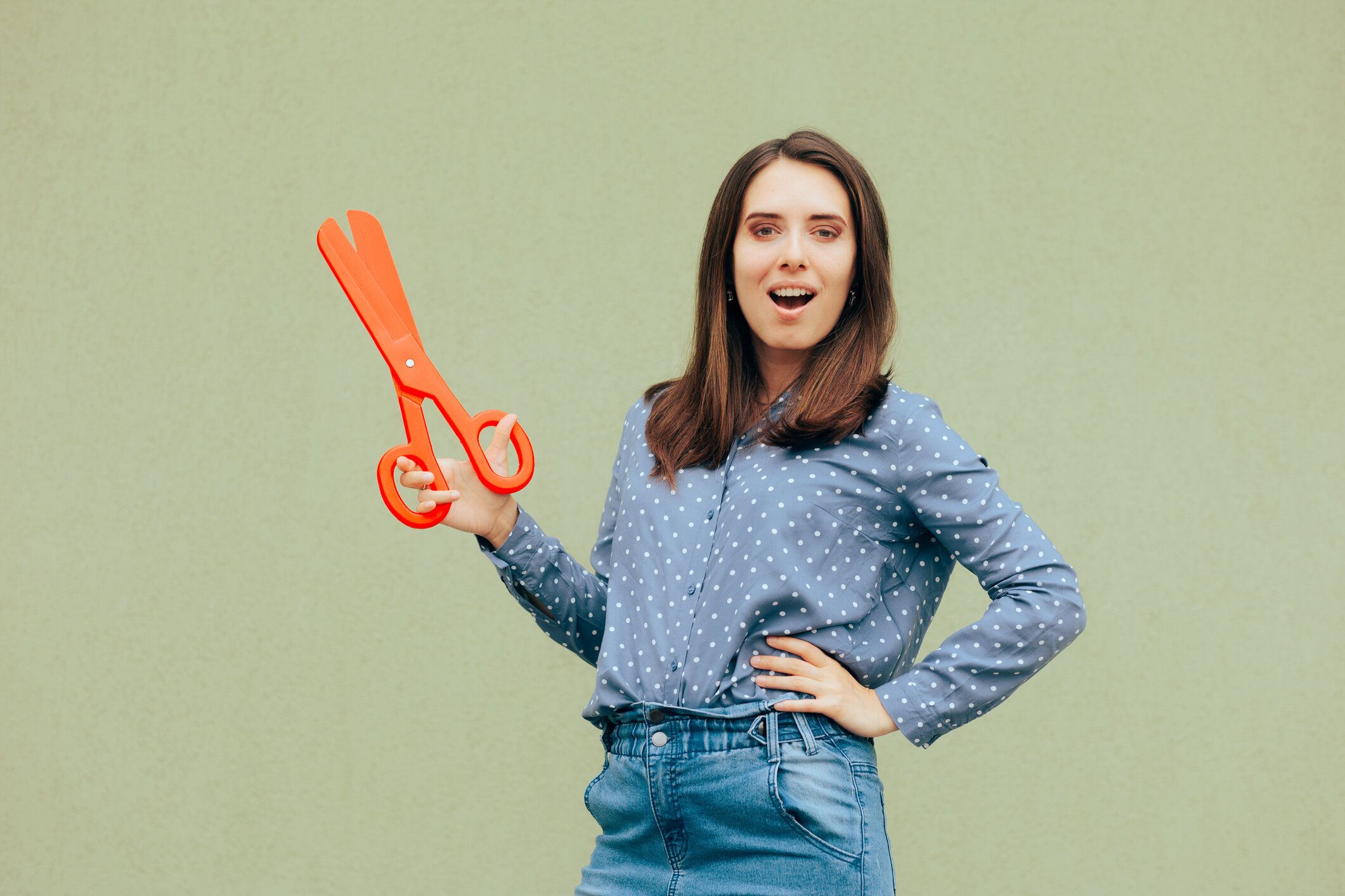 特大の大きな赤いはさみを持っている陽気で面白い女性