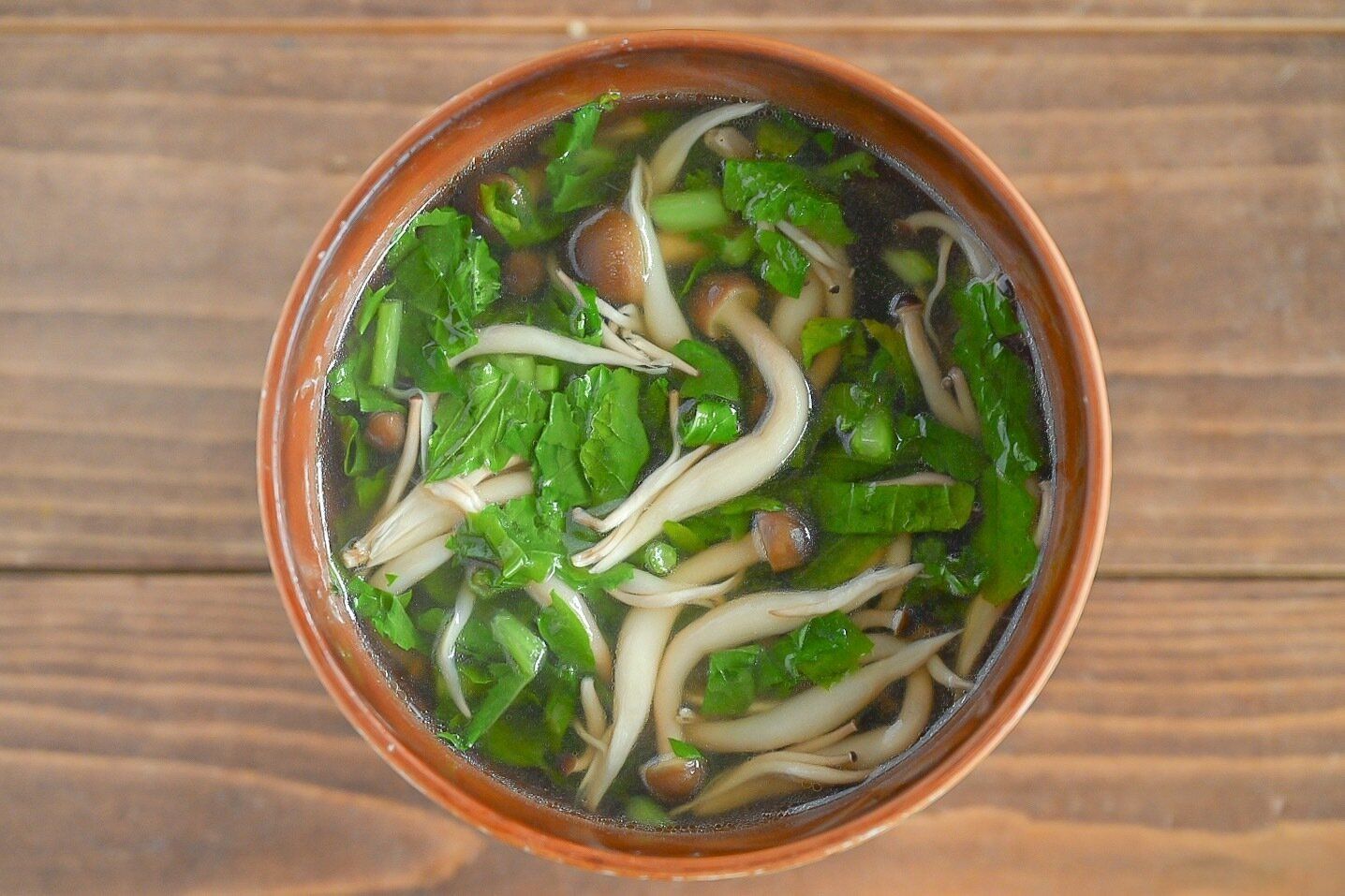 お椀に入った大根の葉としめじの中華スープ