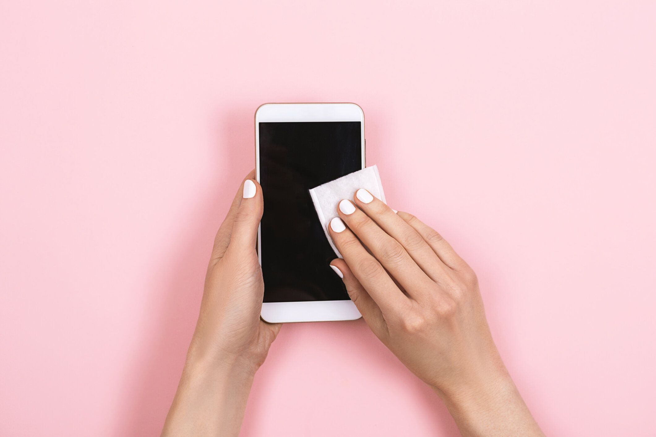 女性はスマートフォンの画面を消毒します。