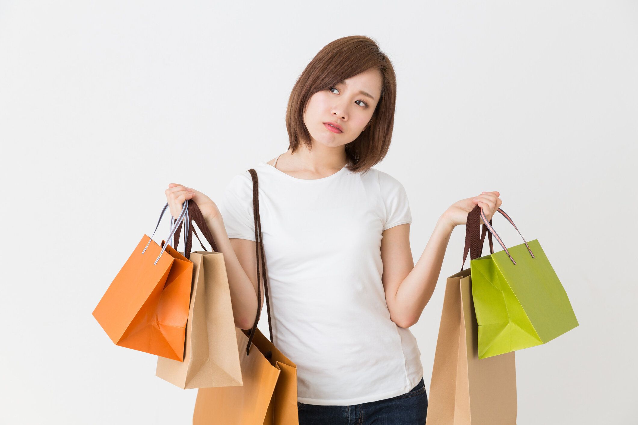 買い物袋を持ちながら考えている女性