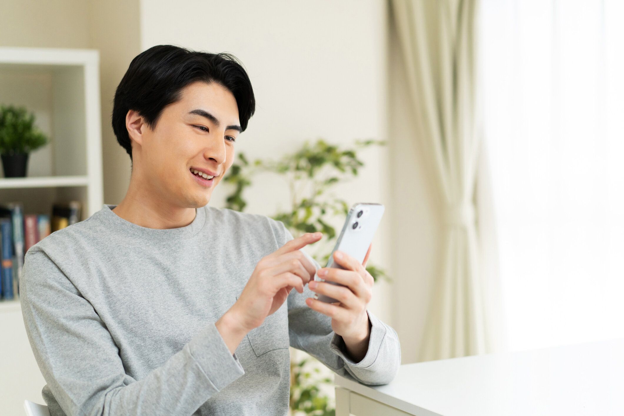 自宅で携帯電話を使う日本人男性