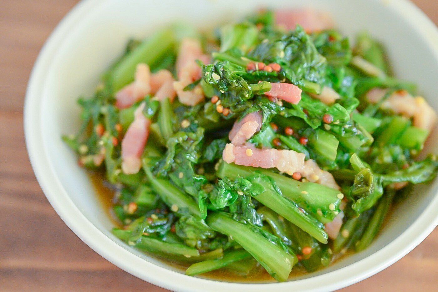 白い皿に盛られたベーコンと春菊のマスタード炒め