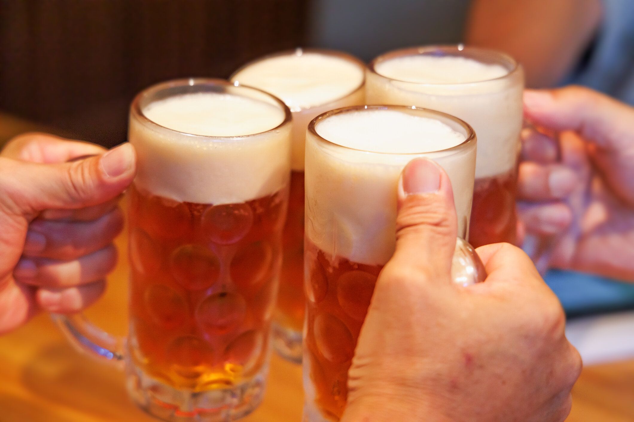 レストランで生ビールのマグカップを乾杯する人々