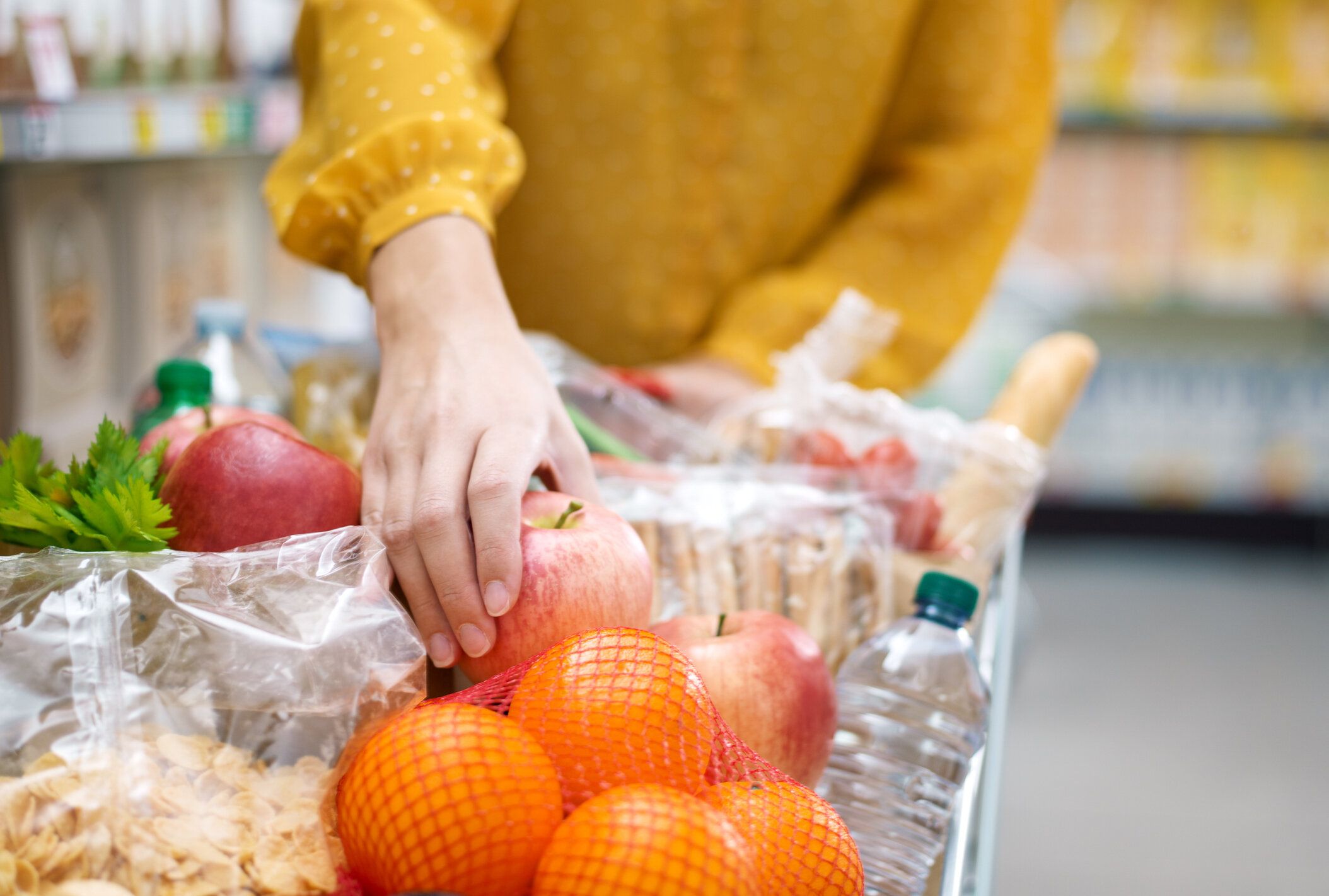 食料品を買い物かごに入れる女性