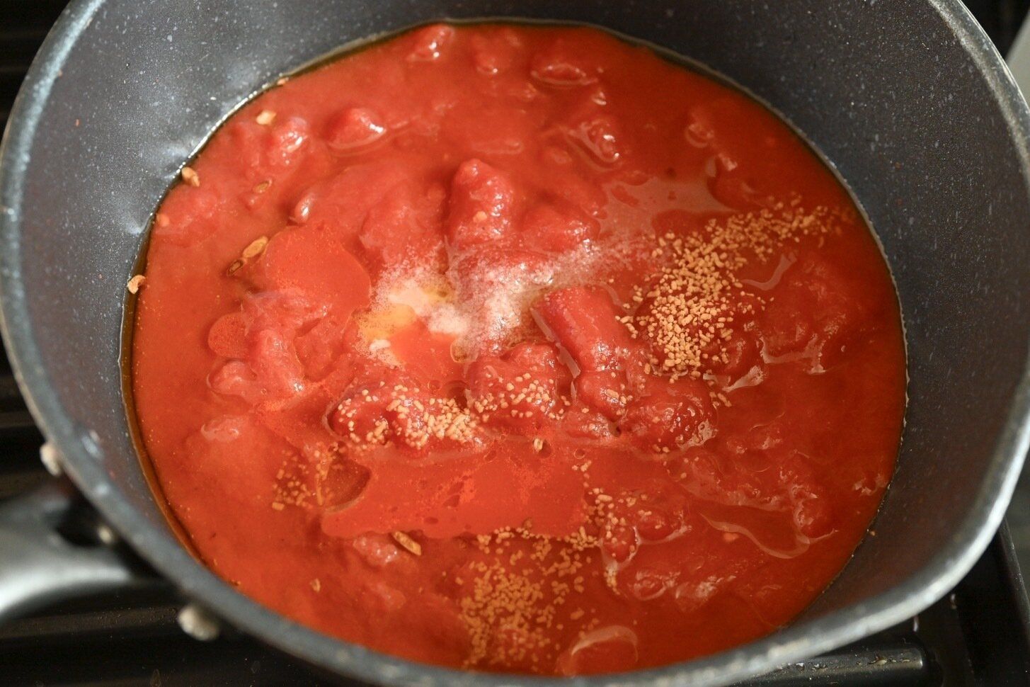 フライパンに入ったトマト缶と調味料