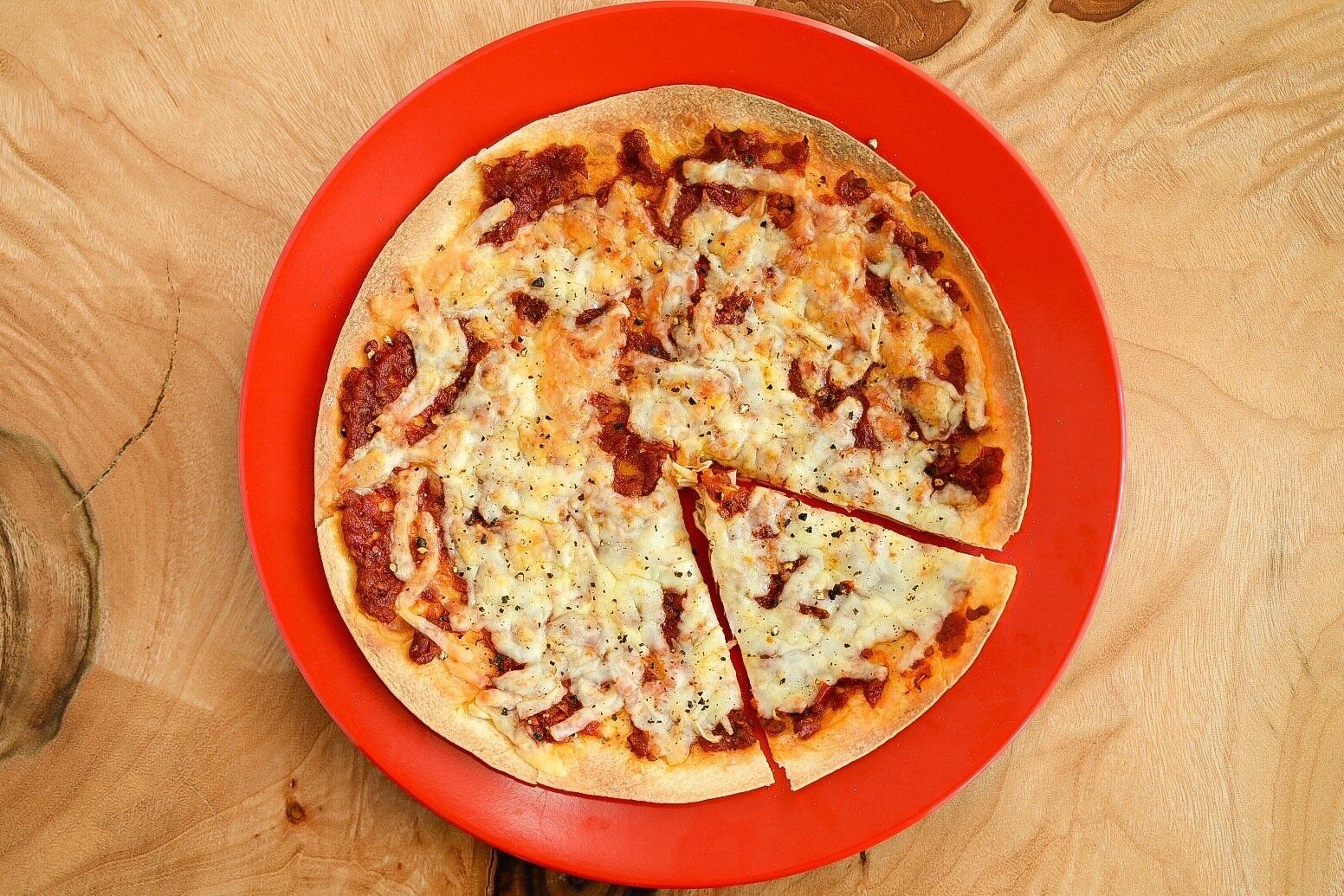 赤い皿に盛られたトマトのピザ