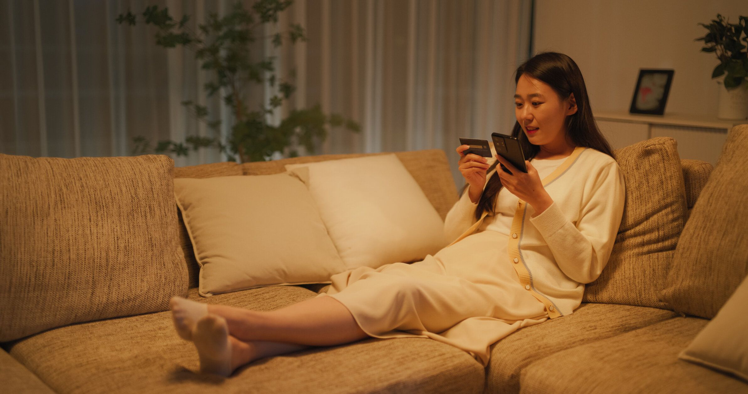 居心地の良いアパートでオンラインショッピングアプリを使用し、スマートフォンとクレジットカードを手に安全な買い物をし、ストリーミングサービスのサブスクリプションを更新する韓�