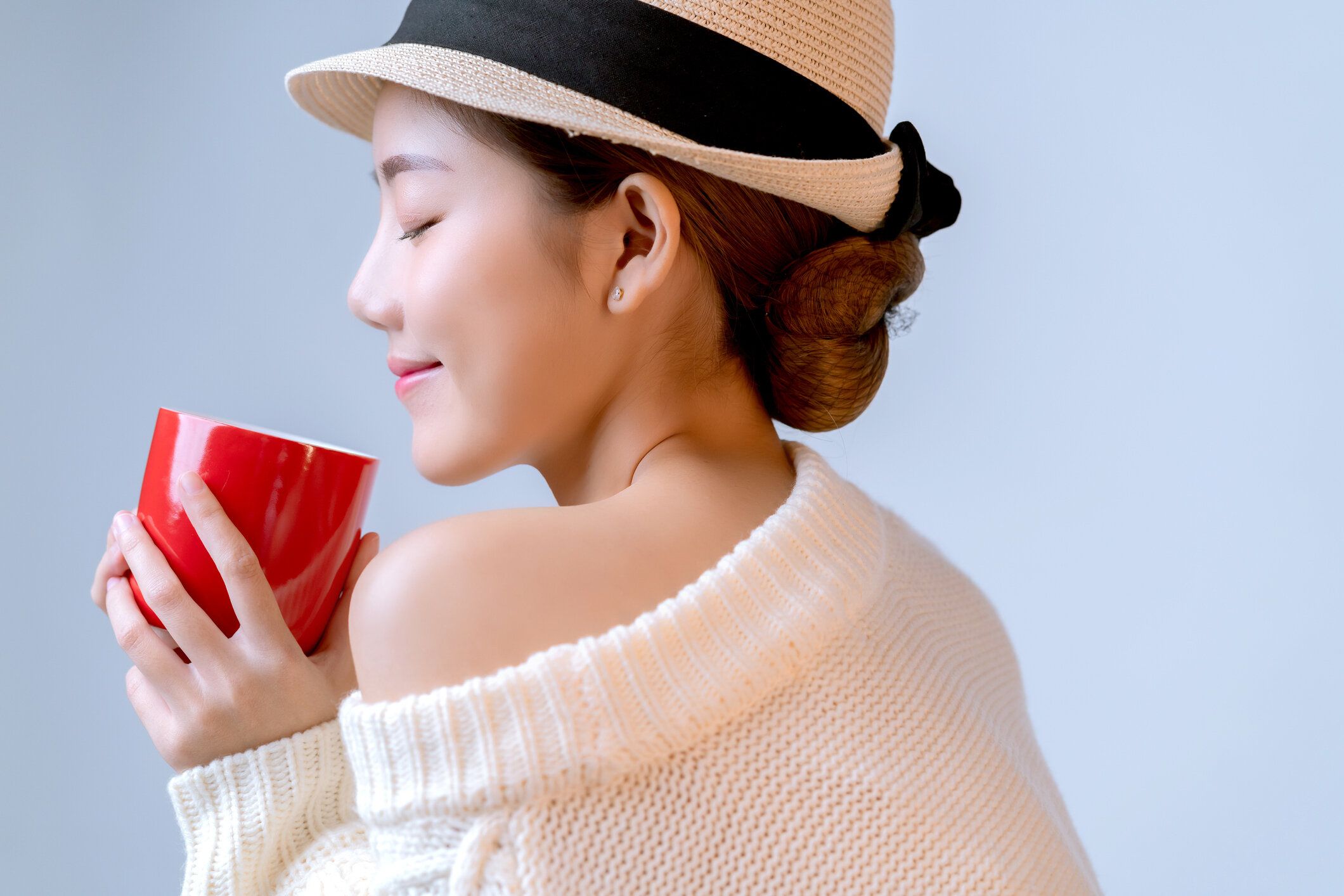 魅力的なアジアの美しい女性の女性の手は、カメラの肖像画スタジオでホットカップコーヒードリンクの外観を持って白い背景を撮影