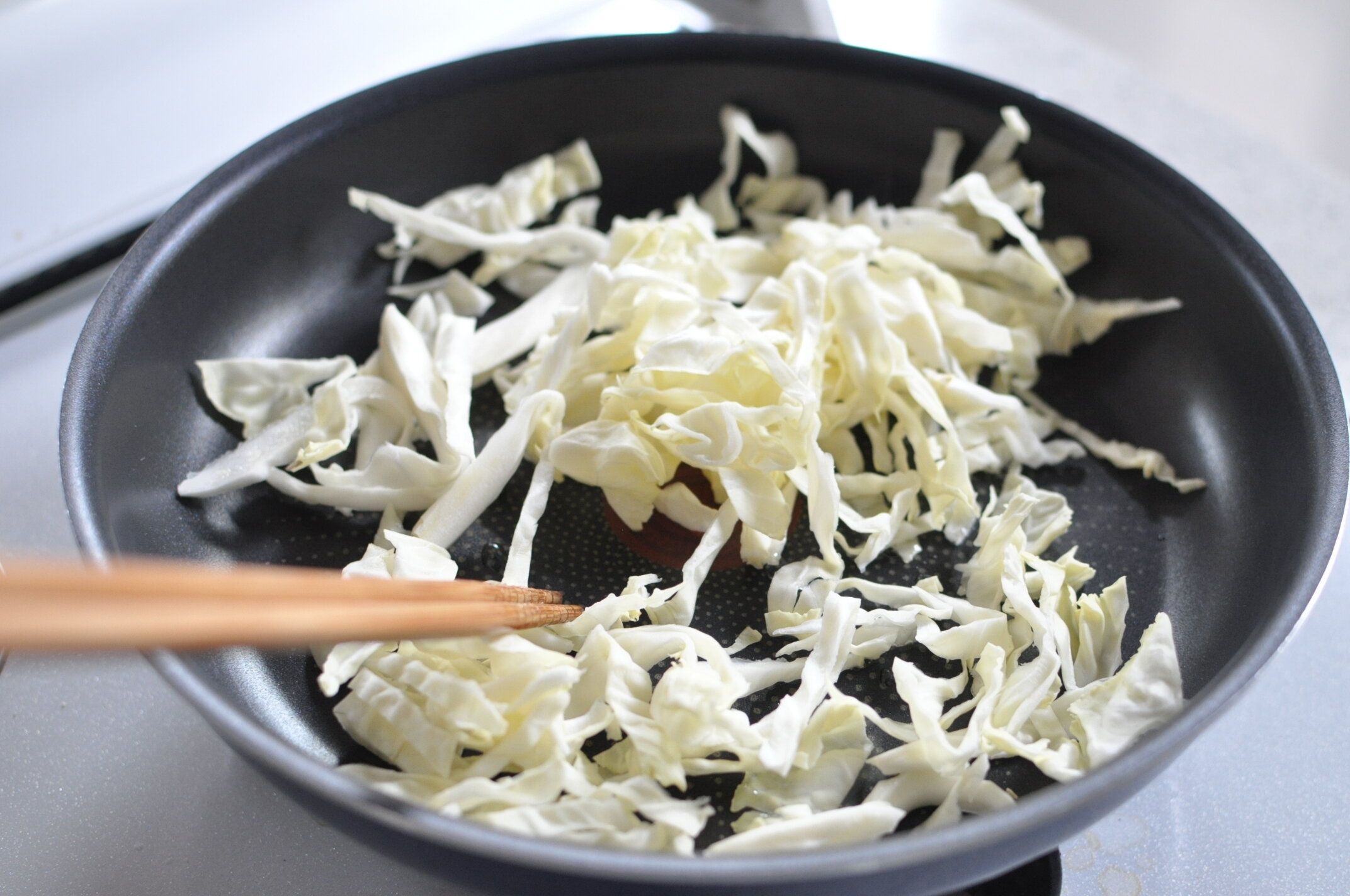 フライパンで千切りキャベツを炒める様子