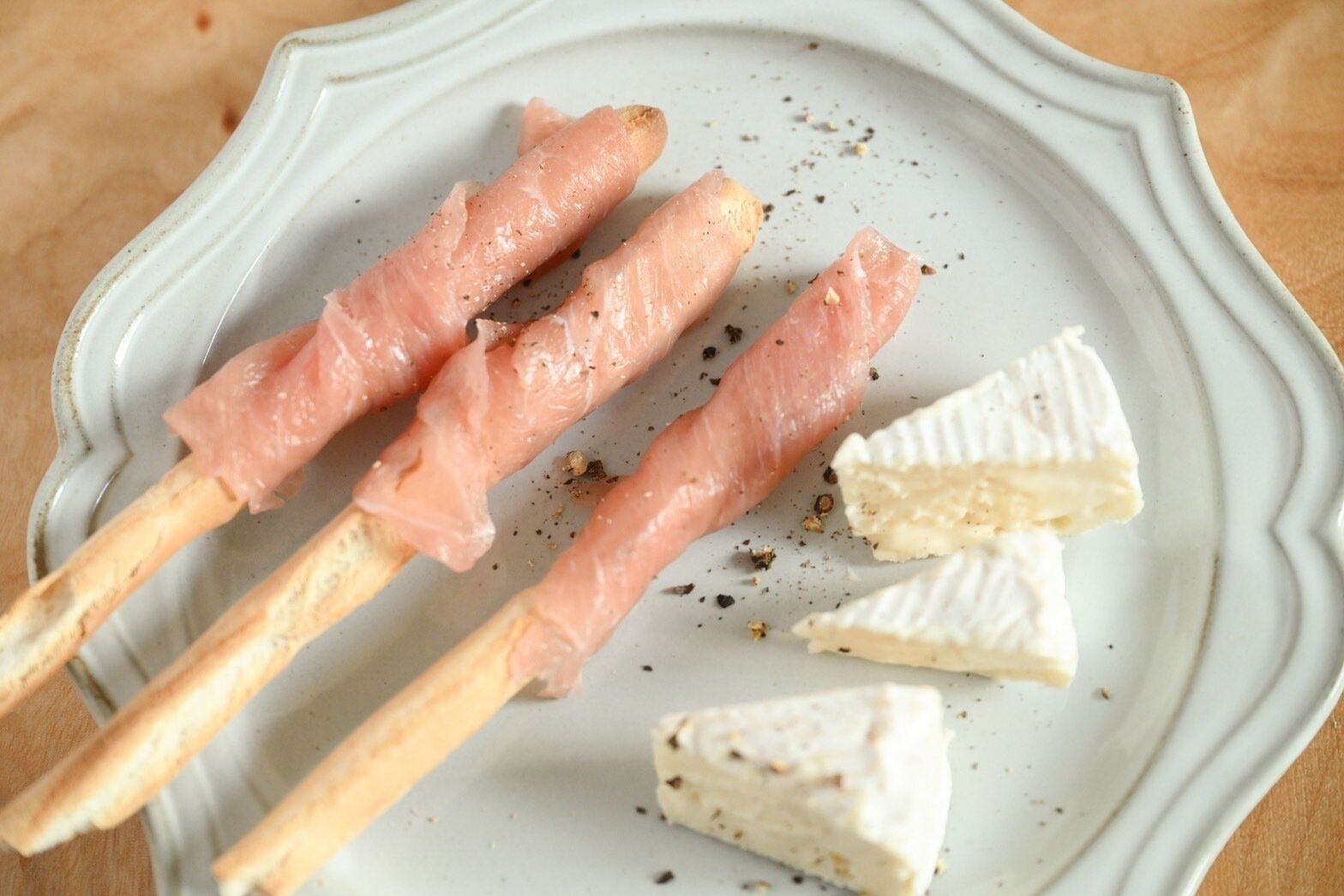 生ハムを巻いたグリッシーニと添えられたチーズ