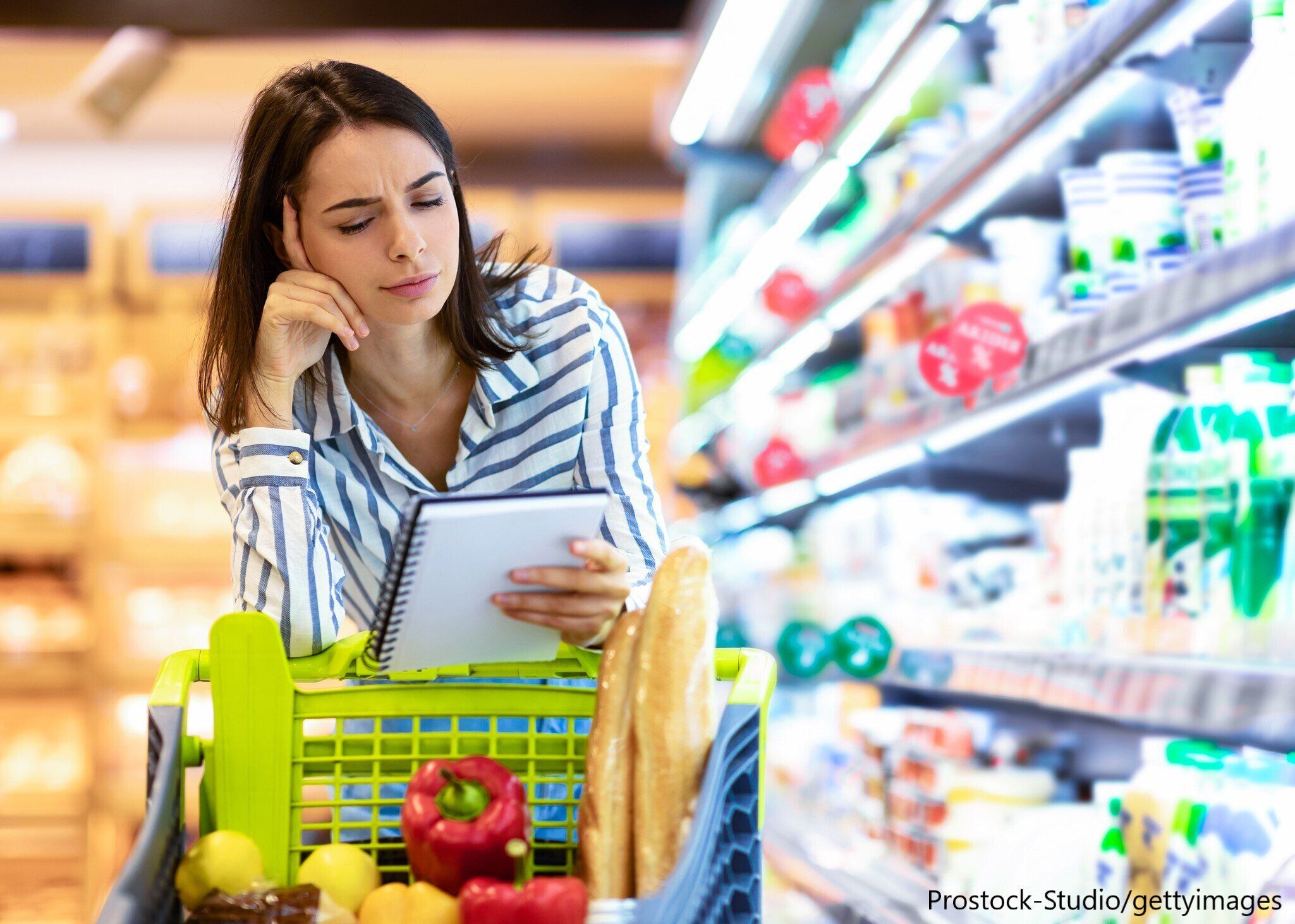 買い物メモを見ながら悩む女性